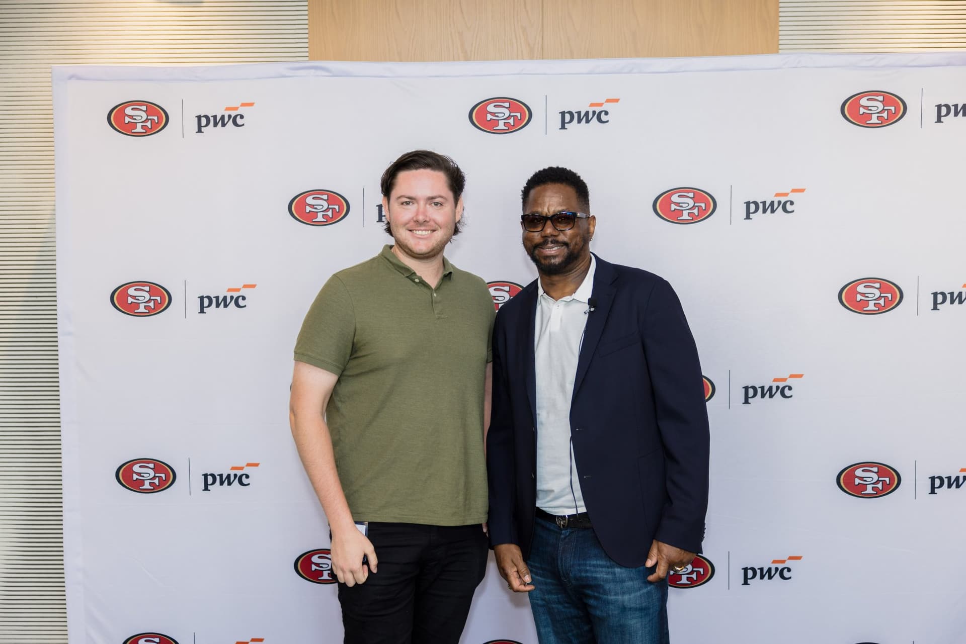 Attendee posing with the 49ers legend at the step-and-repeat at the PwC x 49ers event at PwC Silicon Valley in San Jose by JY Studio