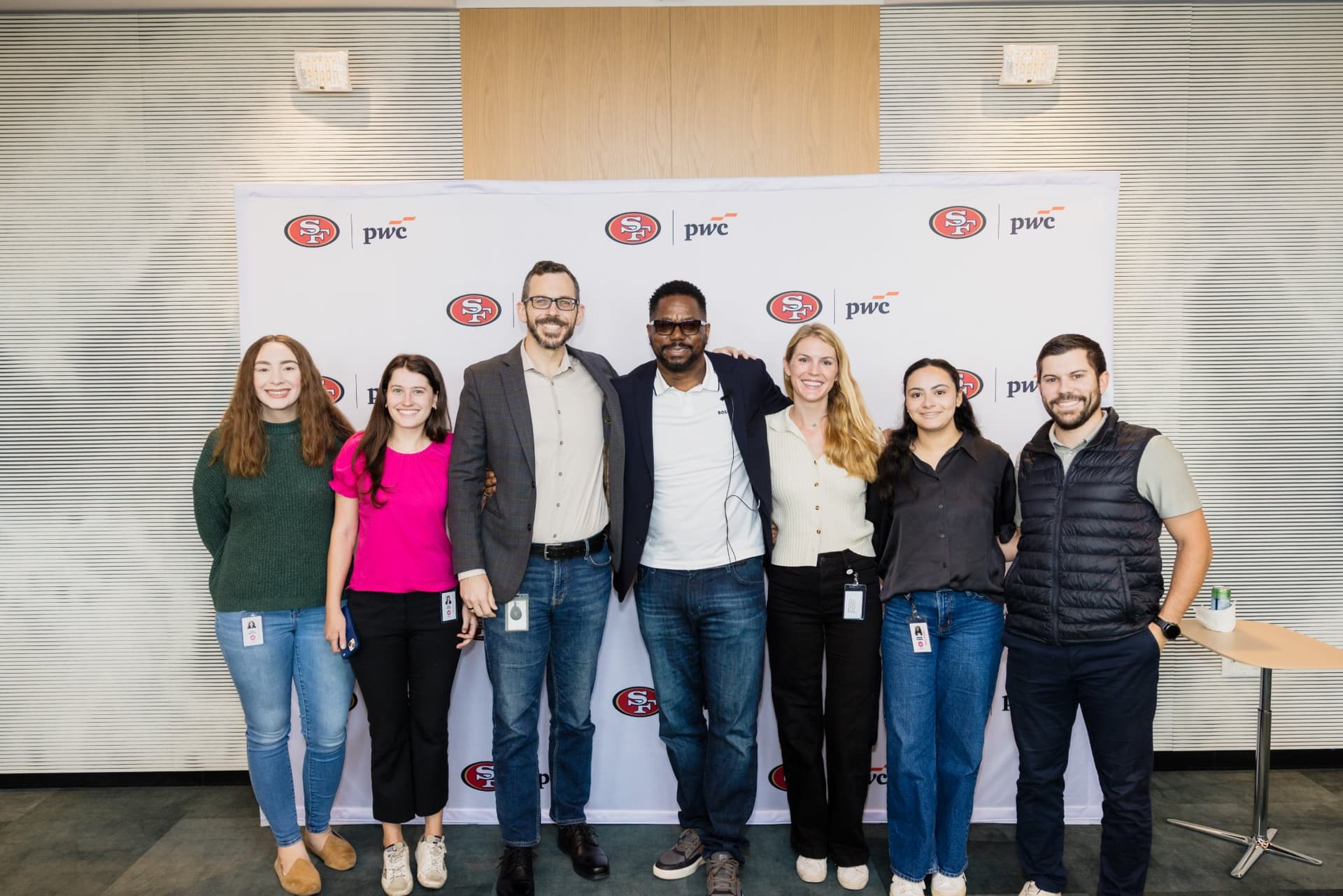 Group of PwC team members posing with the 49ers legend in front of the backdrop at the PwC x 49ers event at PwC Silicon Valley in San Jose by JY Studio