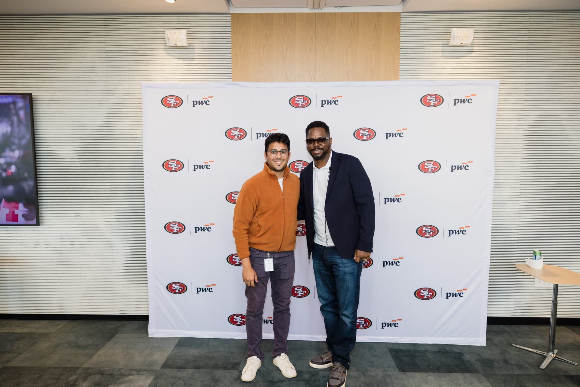 Attendee posing with the 49ers legend at the step-and-repeat at the PwC x 49ers event at PwC Silicon Valley in San Jose by JY Studio