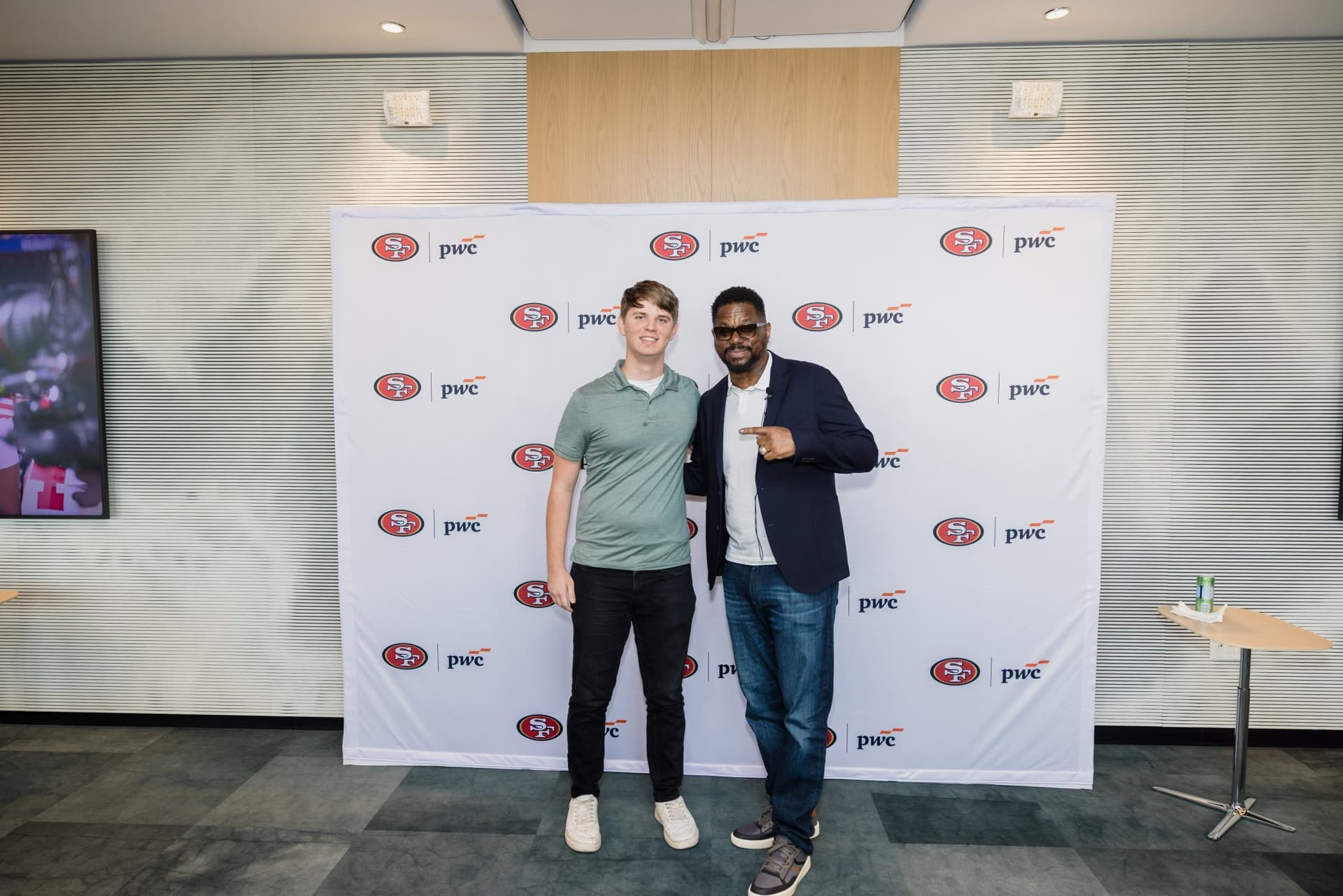 Attendee posing with the 49ers legend at the step-and-repeat at the PwC x 49ers event at PwC Silicon Valley in San Jose by JY Studio