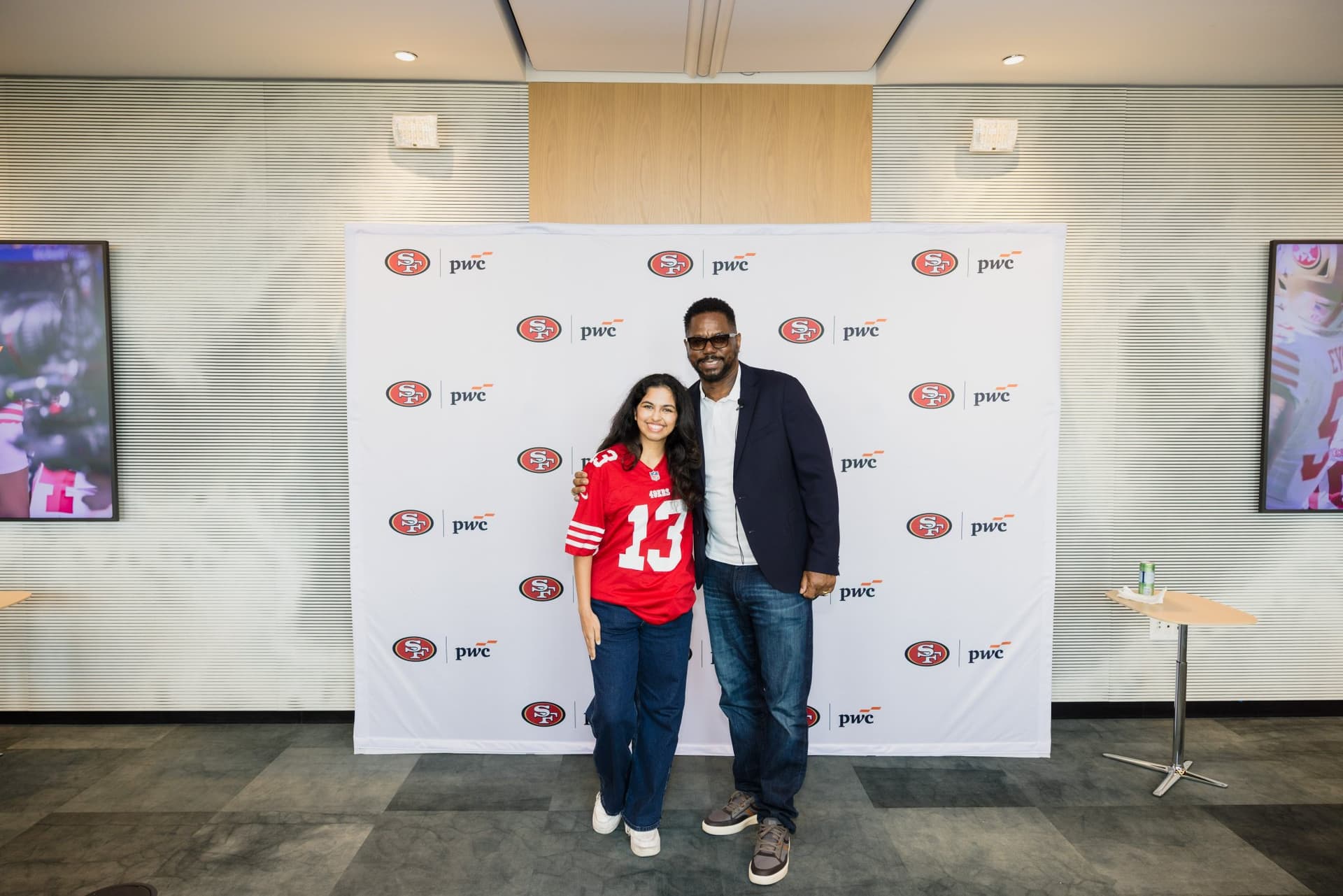 Fan in a number 13 49ers jersey posing with the 49ers legend at the step-and-repeat at the PwC x 49ers event at PwC Silicon Valley in San Jose by JY Studio
