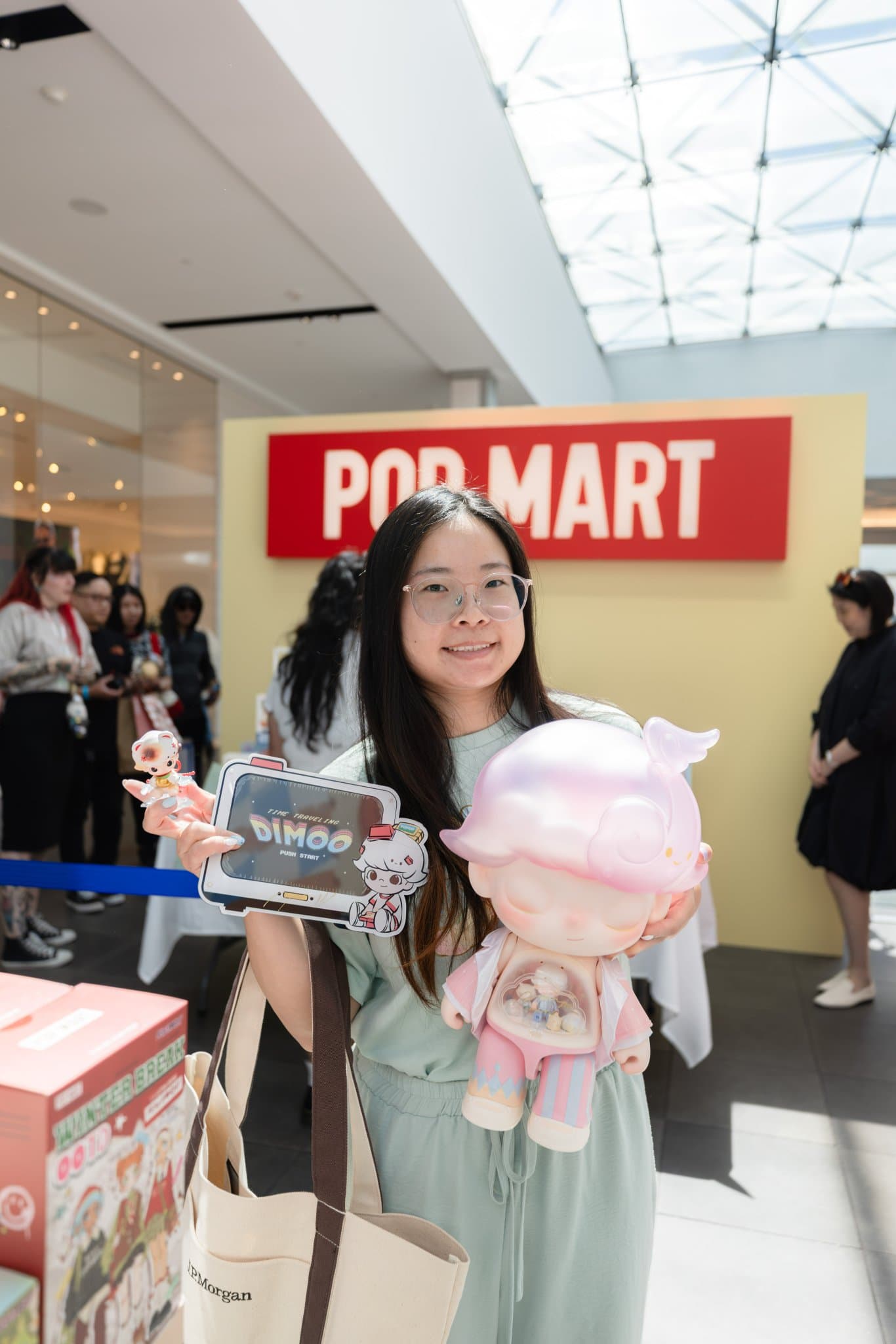 Smiling fan holding a pink DIMOO figure and a signed DIMOO box at the Pop Mart DIMOO signing event at Westfield Valley Fair in Santa Clara by JY Studio