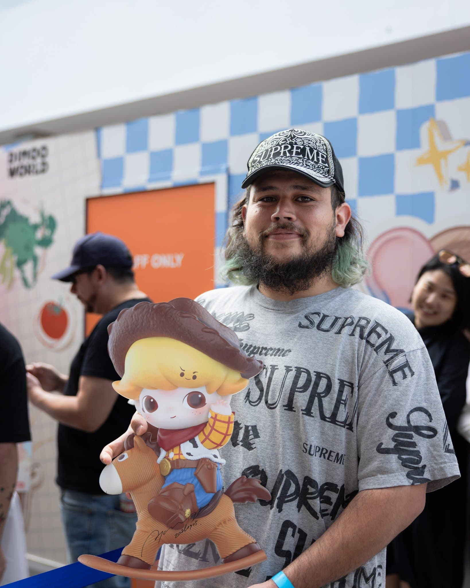Fan holding a cowboy DIMOO x PIXAR figure on a rocking horse at the Pop Mart DIMOO WORLD x PIXAR pop-up at Westfield Valley Fair in Santa Clara by JY Studio