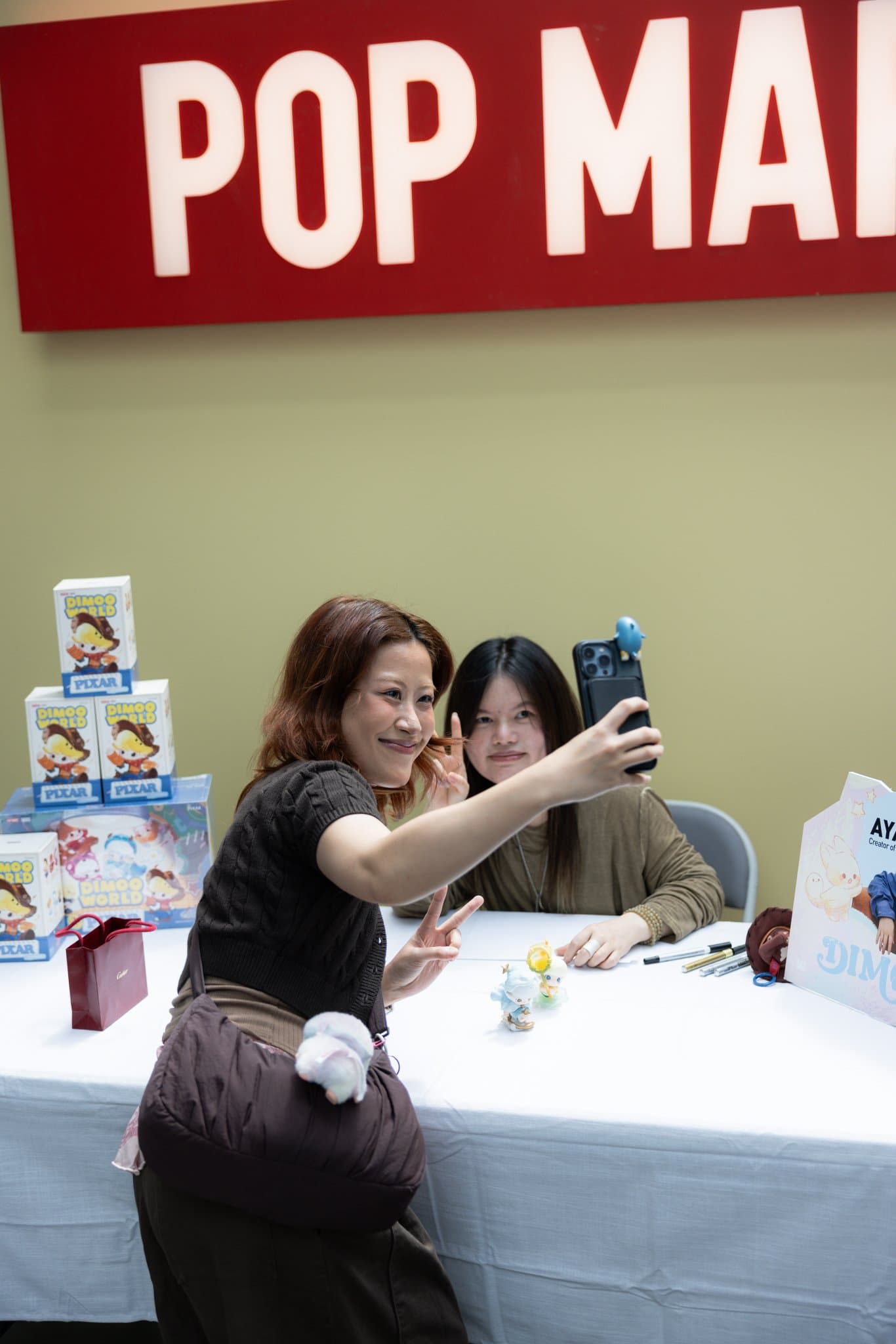 Fan taking a selfie with DIMOO artist Ayan at the signing table at the Pop Mart DIMOO signing event at Westfield Valley Fair in Santa Clara by JY Studio