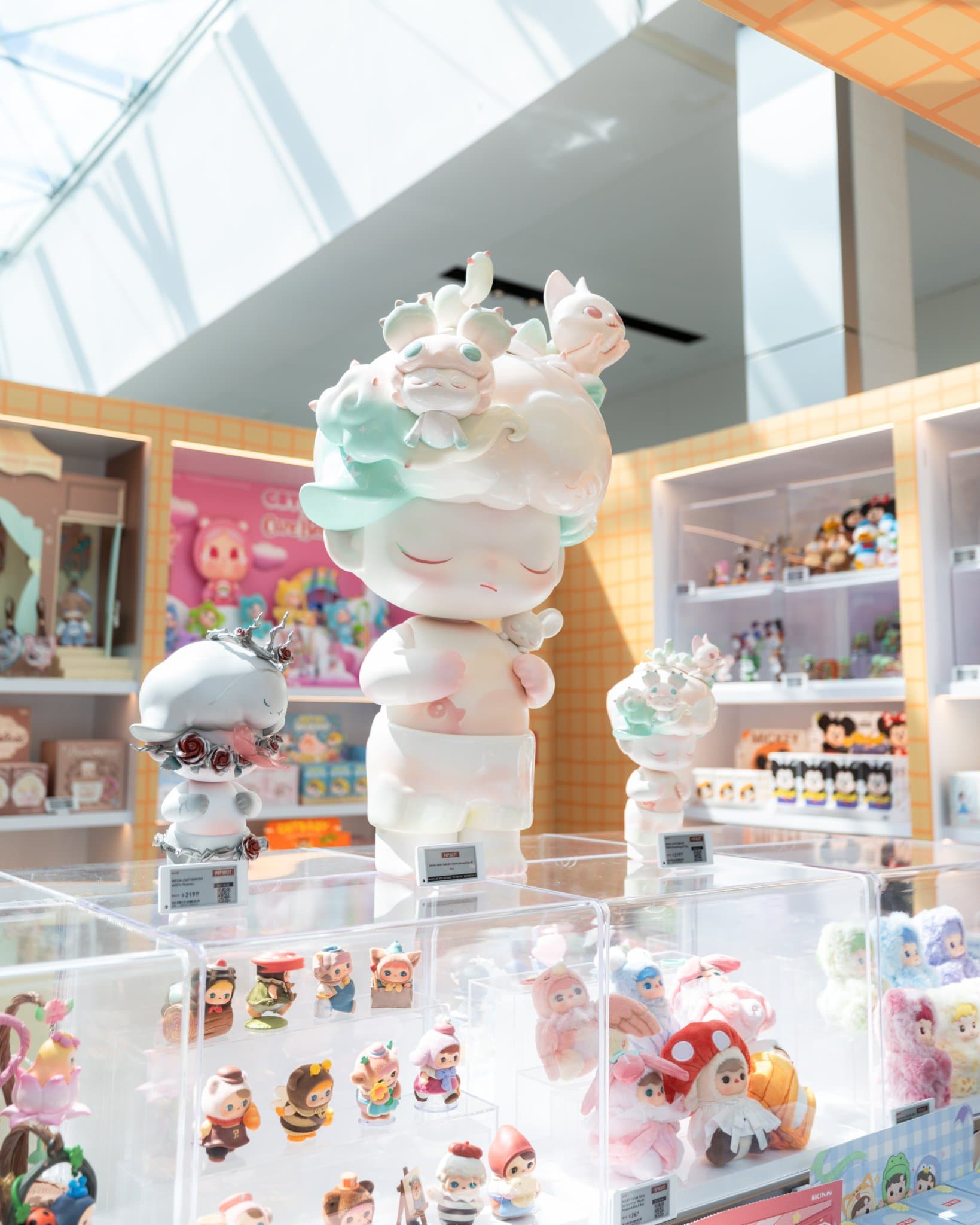 Large white DIMOO sculpture and DIMOO figure display case at the Pop Mart DIMOO WORLD x PIXAR pop-up at Westfield Valley Fair in Santa Clara by JY Studio
