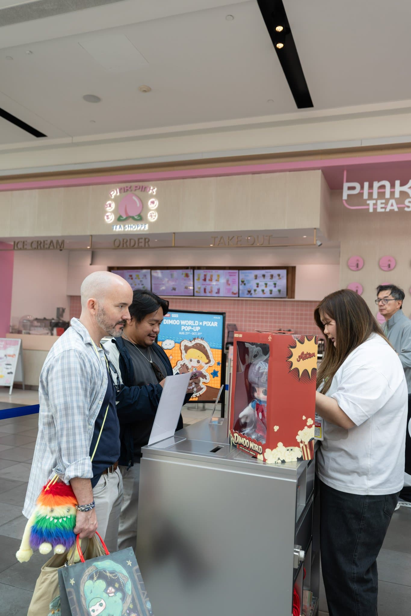 Collectors checking in at the DIMOO pop-up counter beside Pink Pink Tea Shoppe at the Pop Mart DIMOO WORLD x PIXAR pop-up at Westfield Valley Fair in Santa Clara by JY Studio
