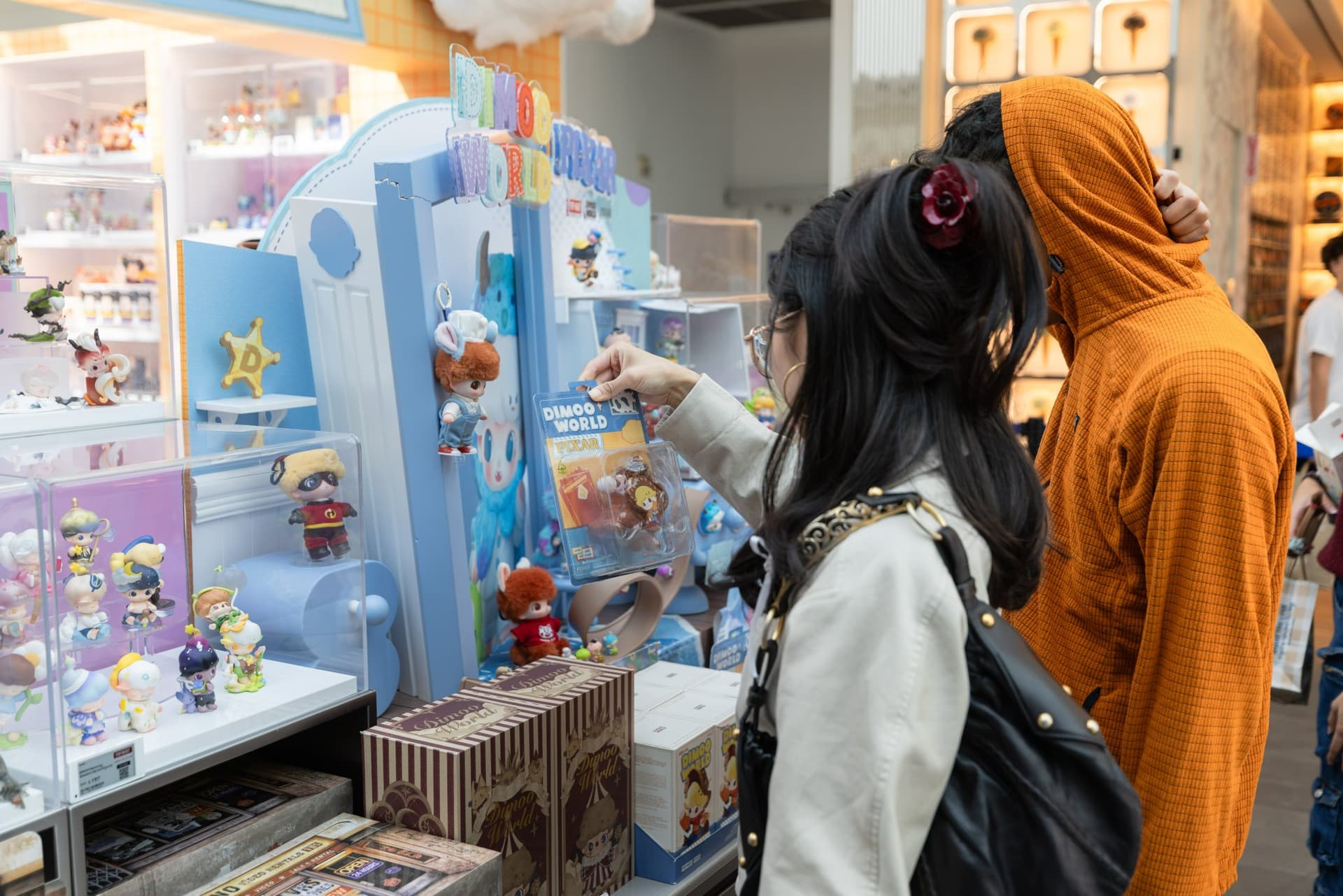 Shoppers browsing DIMOO WORLD x PIXAR blind boxes and figures at the Pop Mart DIMOO WORLD x PIXAR pop-up at Westfield Valley Fair in Santa Clara by JY Studio