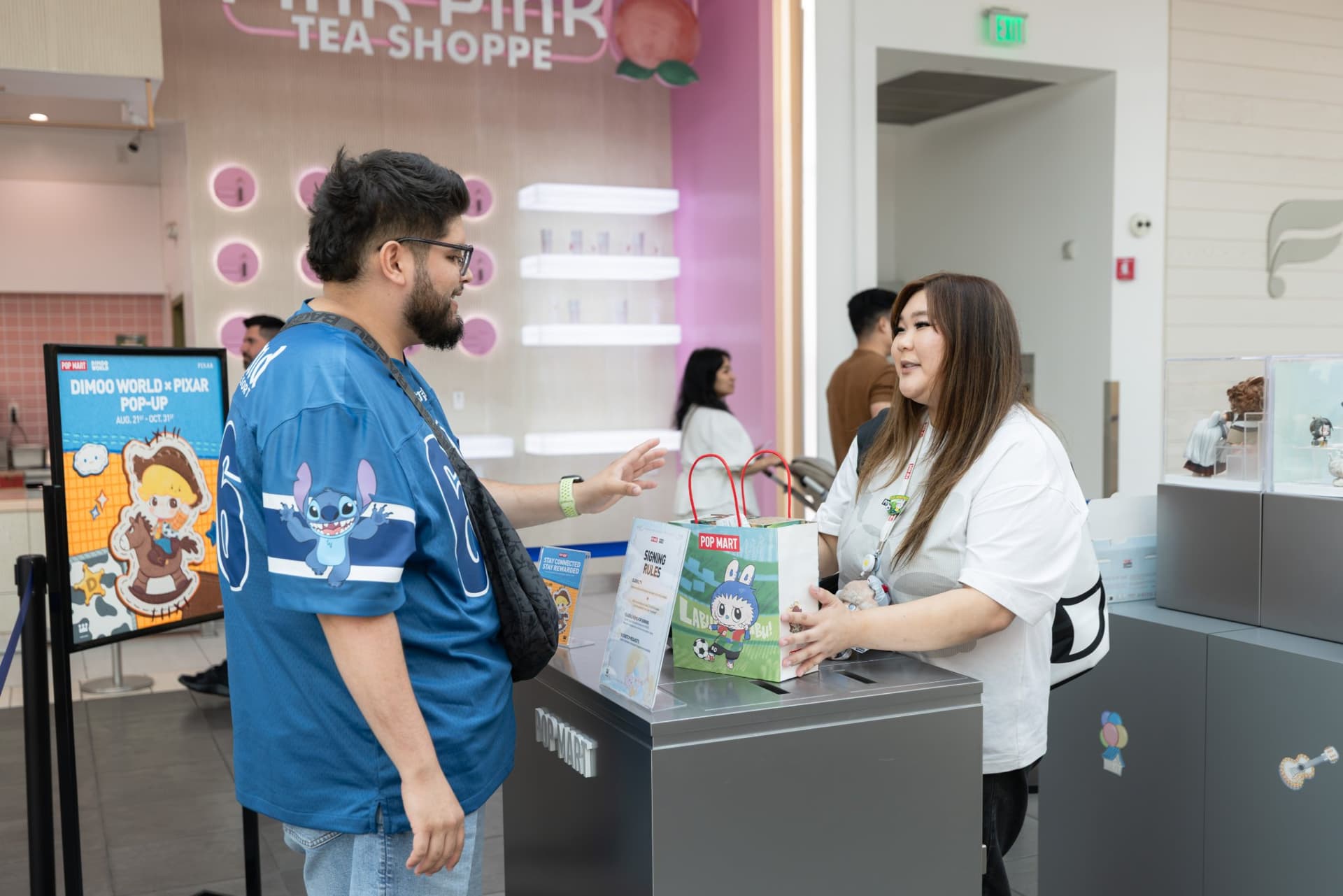 Fan in a Stitch jersey checking out at the DIMOO pop-up at the Pop Mart DIMOO WORLD x PIXAR pop-up at Westfield Valley Fair in Santa Clara by JY Studio