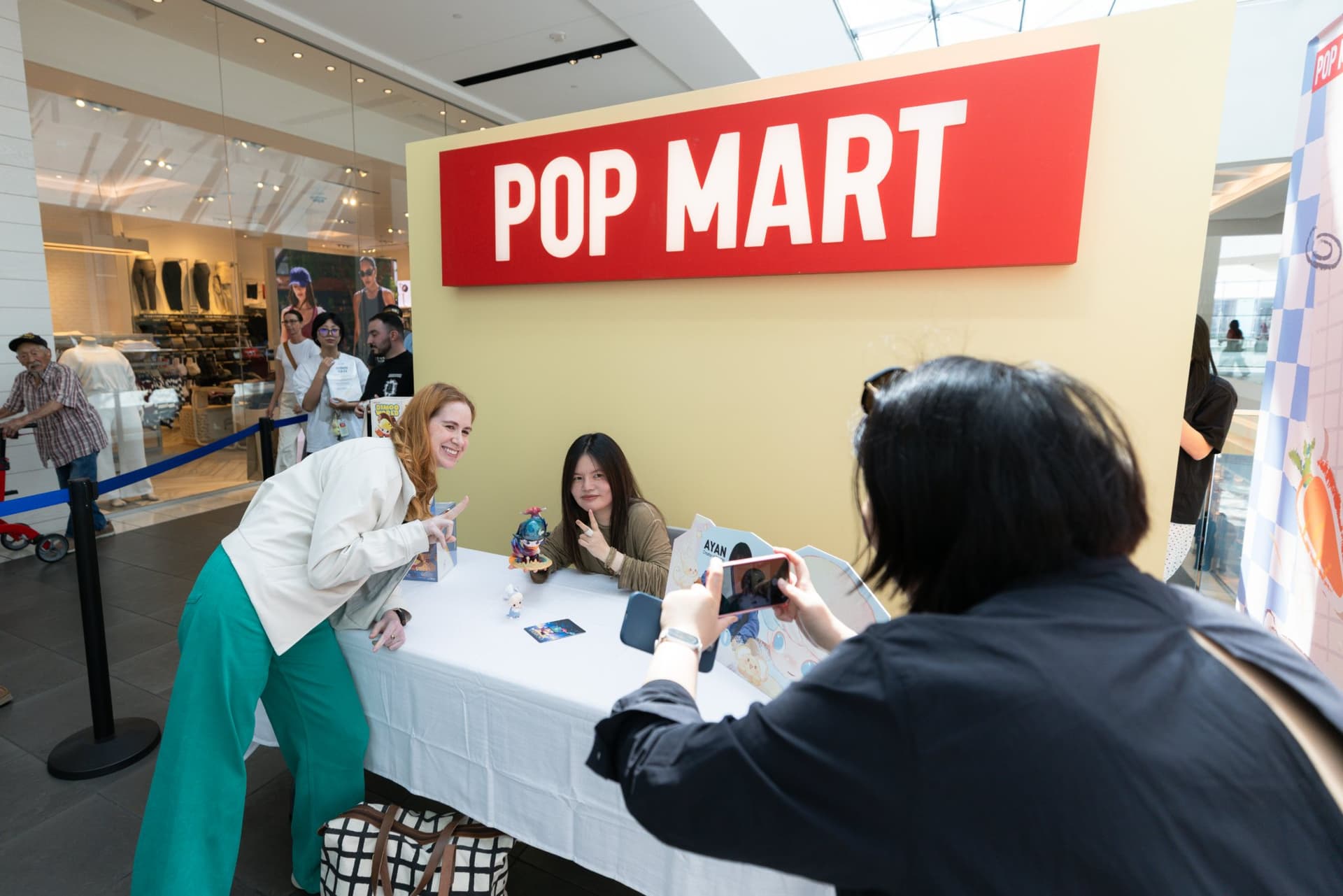 Fan photographing DIMOO creator Ayan during the signing at the Pop Mart DIMOO signing event at Westfield Valley Fair in Santa Clara by JY Studio