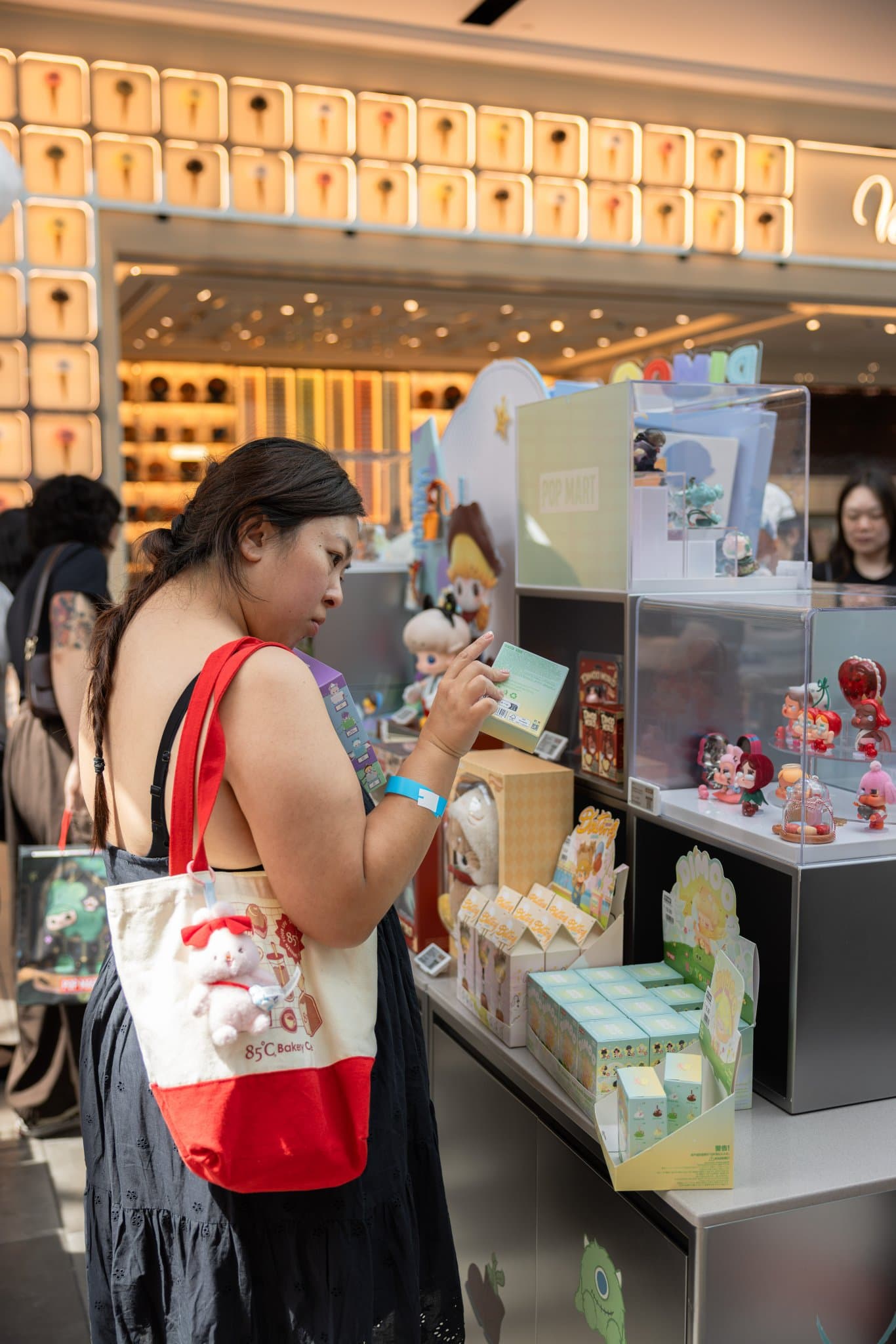 Collector browsing DIMOO figures in the pop-up display cases at the Pop Mart DIMOO WORLD x PIXAR pop-up at Westfield Valley Fair in Santa Clara by JY Studio