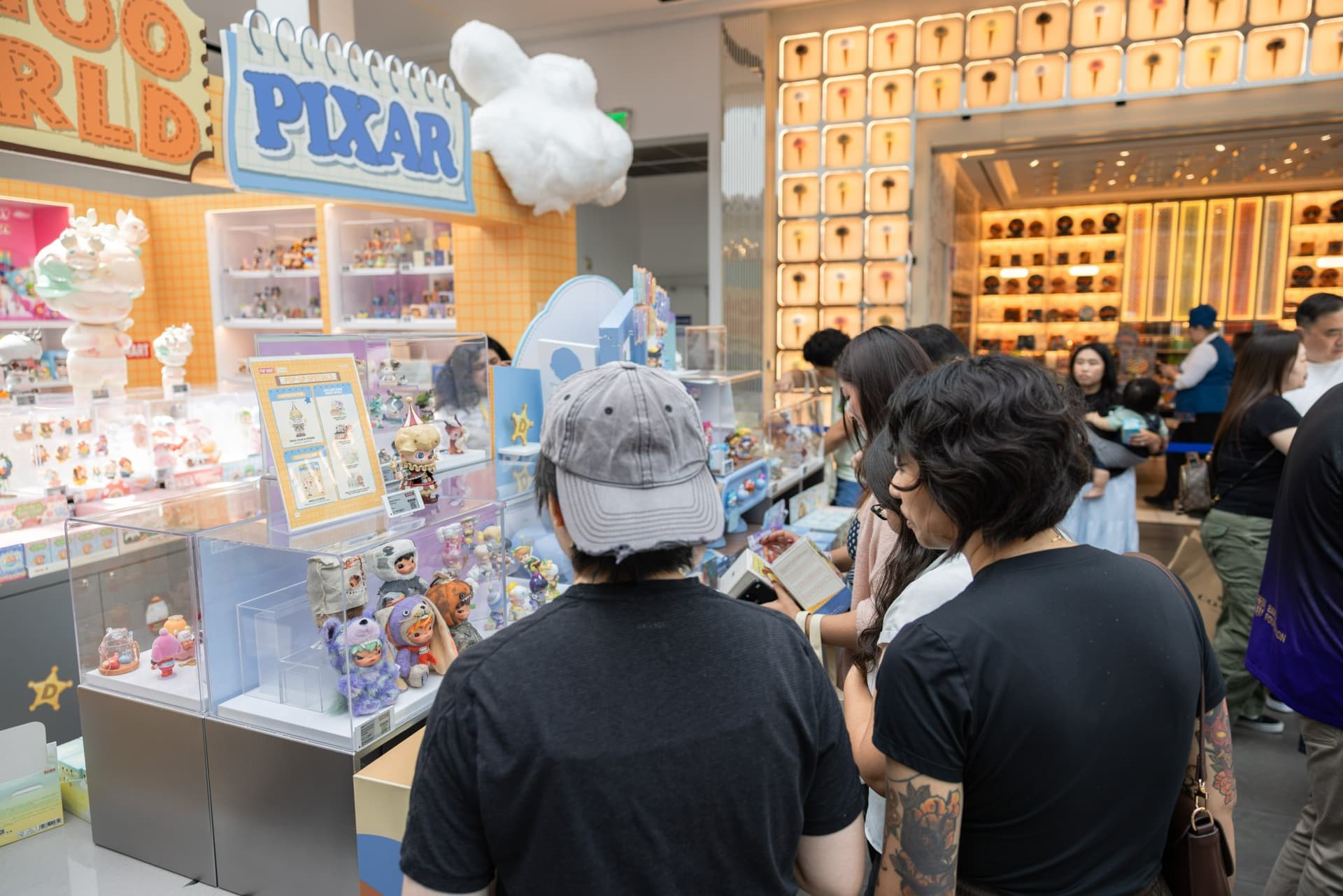 Crowd of collectors at the DIMOO WORLD x PIXAR display counter at the Pop Mart DIMOO WORLD x PIXAR pop-up at Westfield Valley Fair in Santa Clara by JY Studio