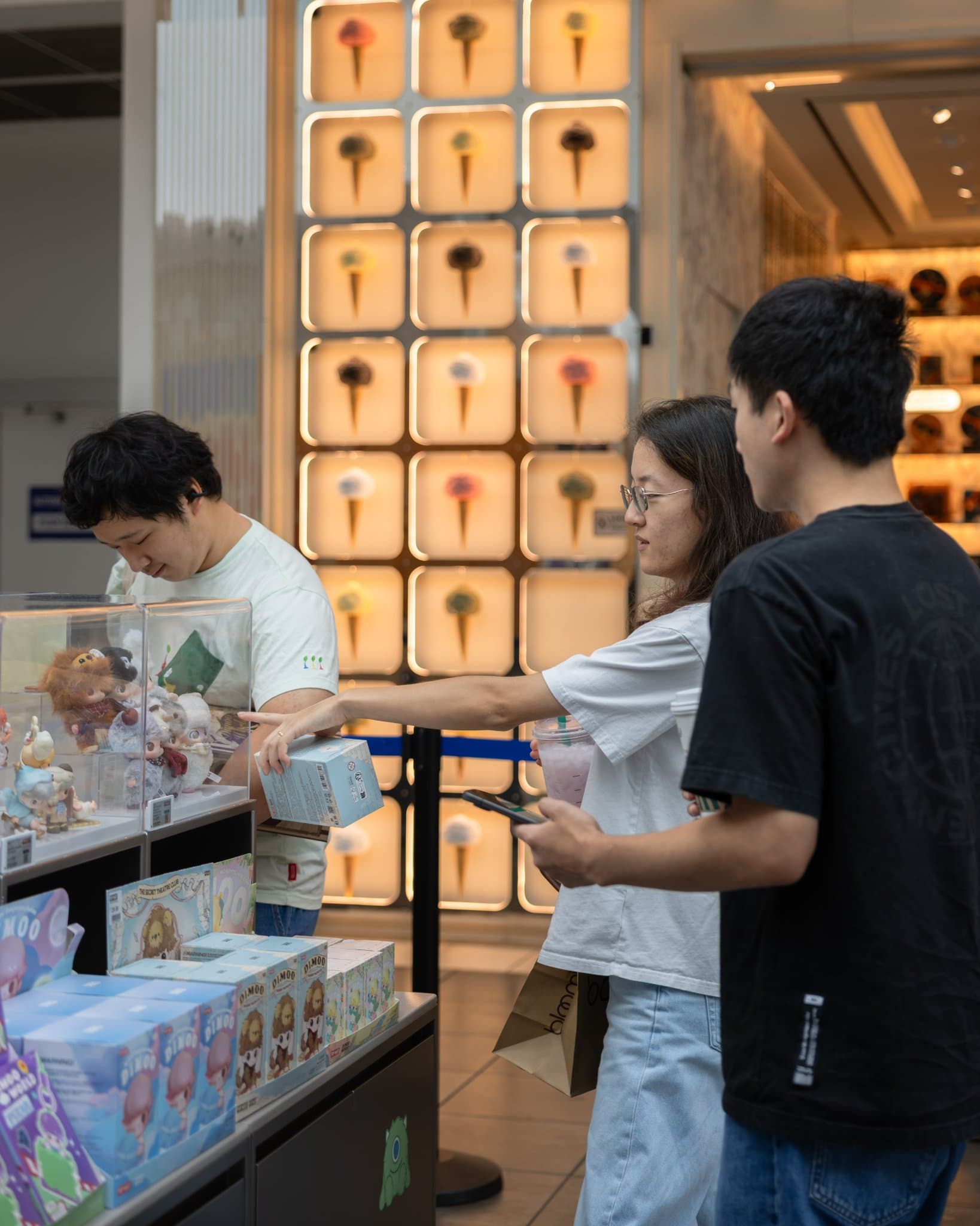 Shoppers browsing DIMOO figures in front of the Pop Mart store wall at the Pop Mart DIMOO WORLD x PIXAR pop-up at Westfield Valley Fair in Santa Clara by JY Studio