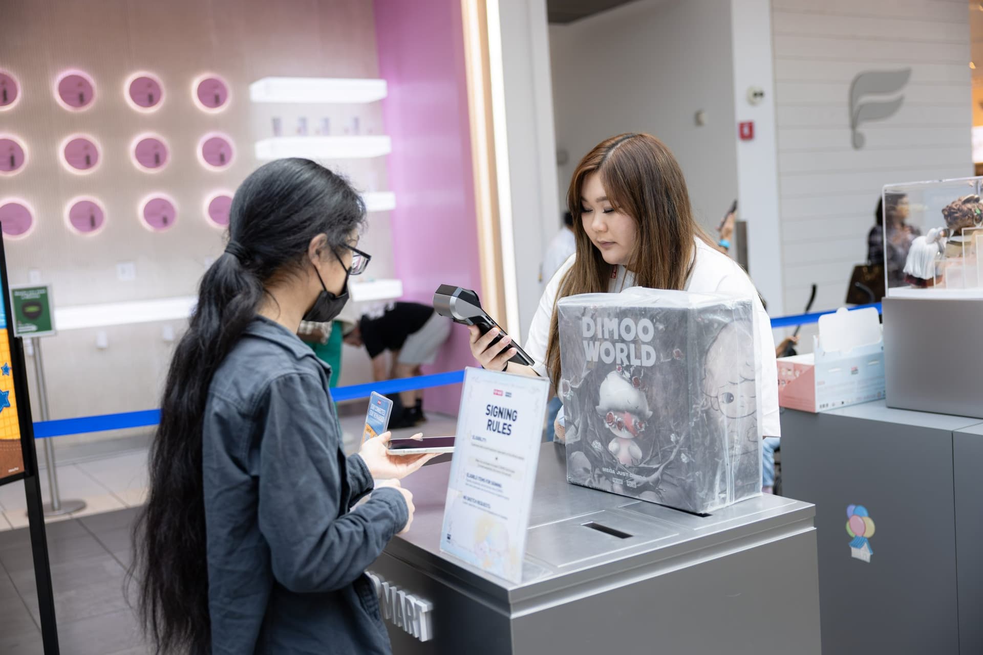 Fan picking up a DIMOO WORLD figure at the Pink Pink Tea Shoppe counter at the Pop Mart DIMOO WORLD x PIXAR pop-up at Westfield Valley Fair in Santa Clara by JY Studio