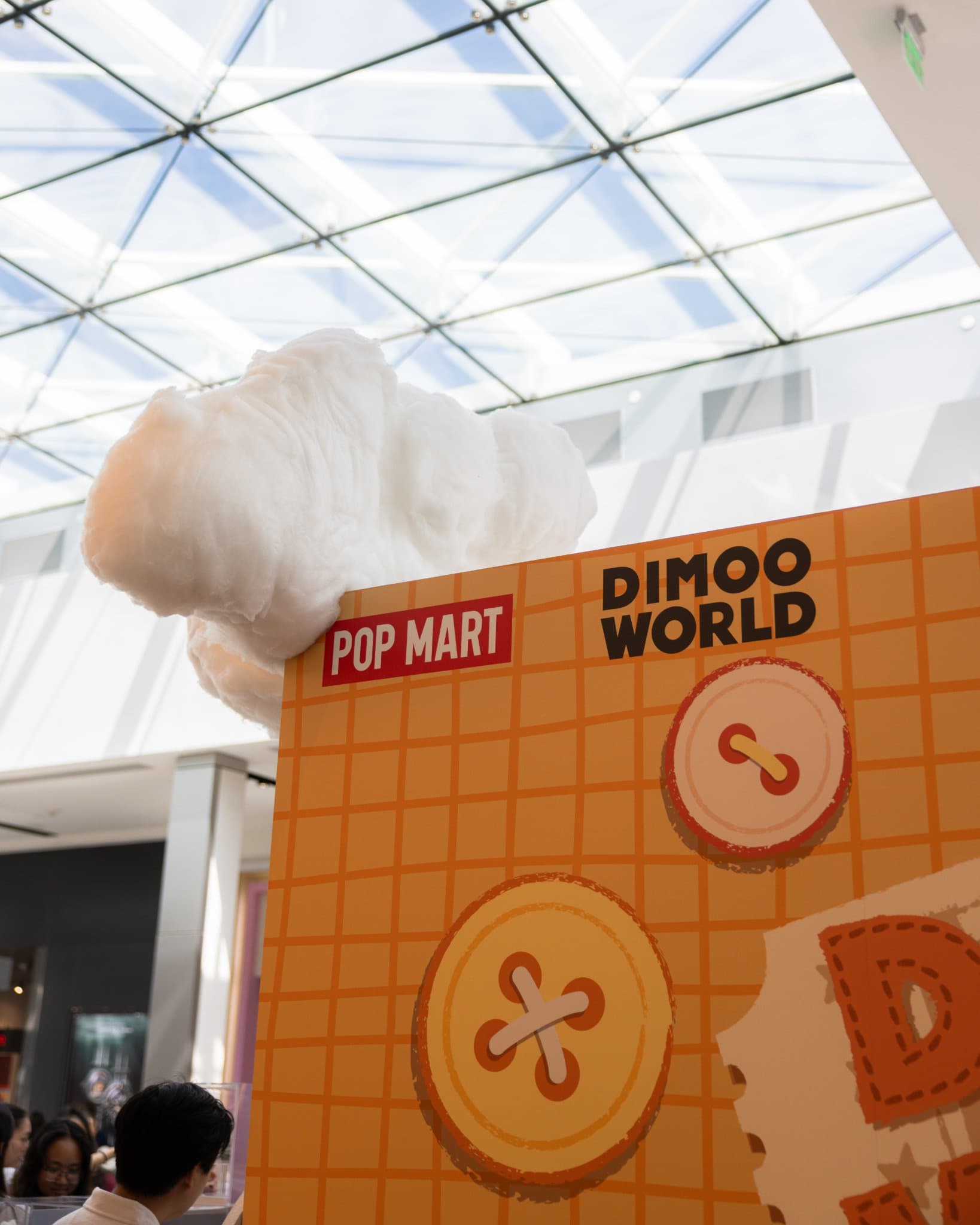 DIMOO WORLD and Pop Mart booth wall with button decorations and a cloud at the Pop Mart DIMOO WORLD x PIXAR pop-up at Westfield Valley Fair in Santa Clara by JY Studio