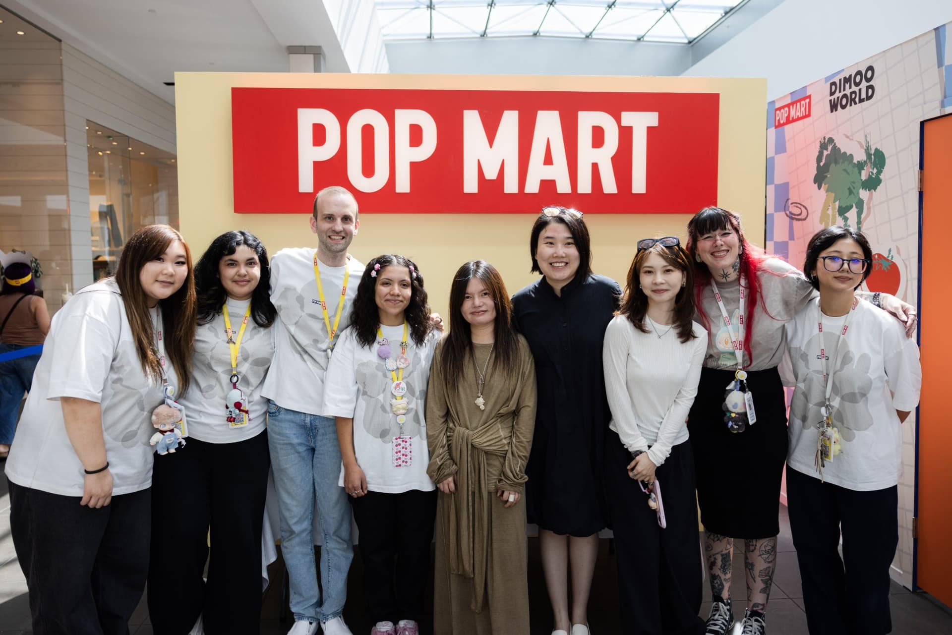 Pop Mart team group photo with DIMOO creator Ayan under the Pop Mart sign at the Pop Mart DIMOO signing event at Westfield Valley Fair in Santa Clara by JY Studio