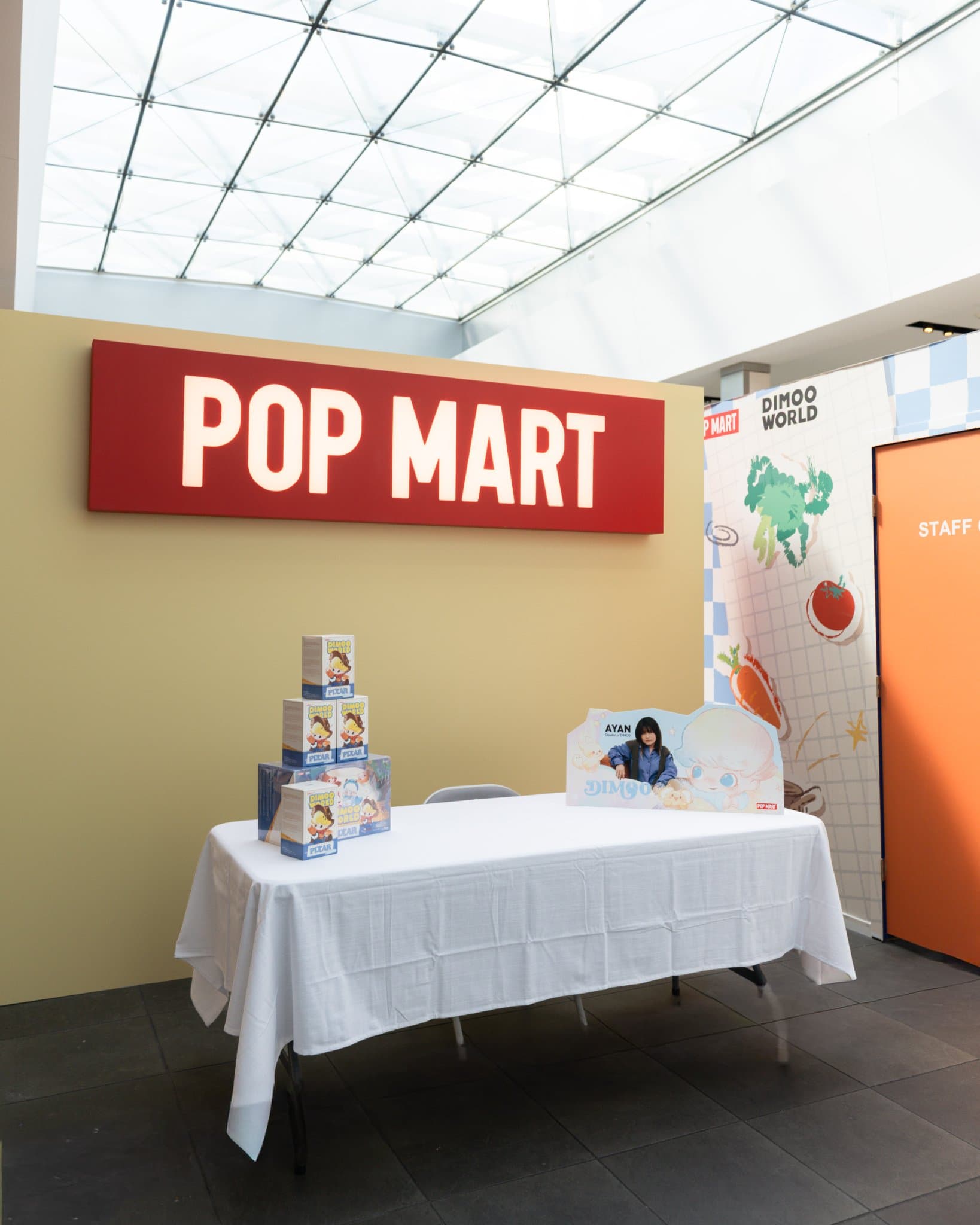 Empty DIMOO signing table under the red Pop Mart sign before the fans arrive at the Pop Mart DIMOO signing event at Westfield Valley Fair in Santa Clara by JY Studio