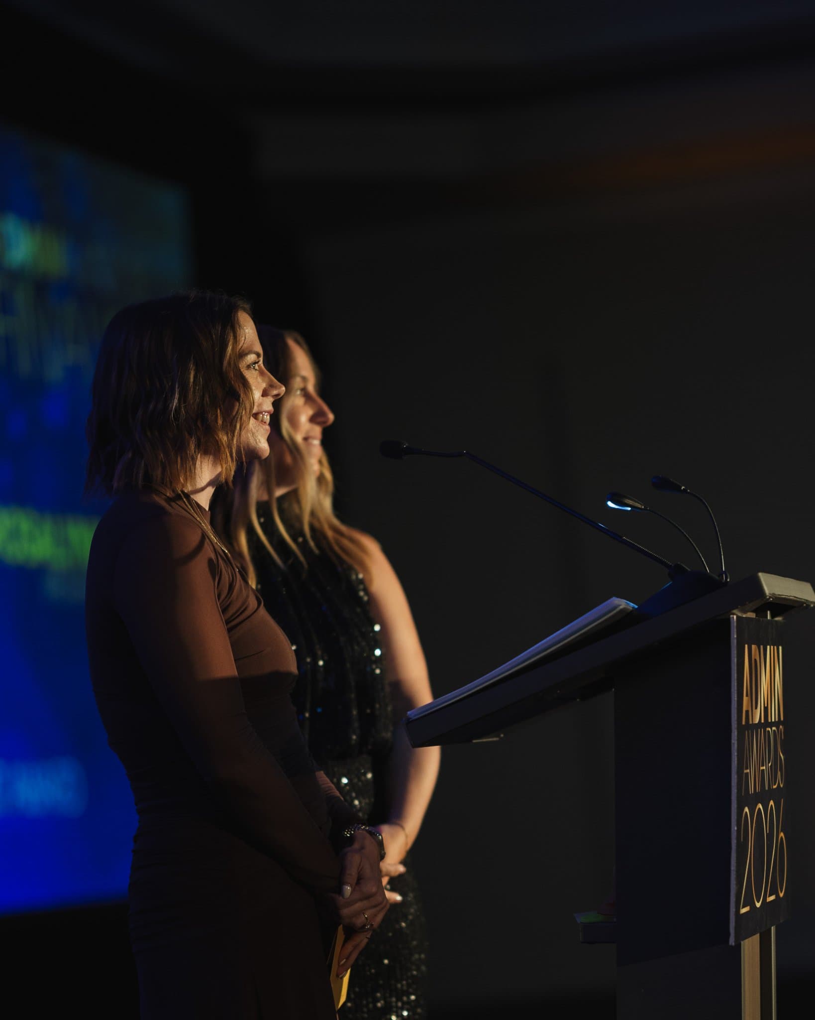 Two honorees standing together at the podium during the ceremony at Admin Awards 2026 at SFO Marriott Waterfront, Burlingame by JY Studio