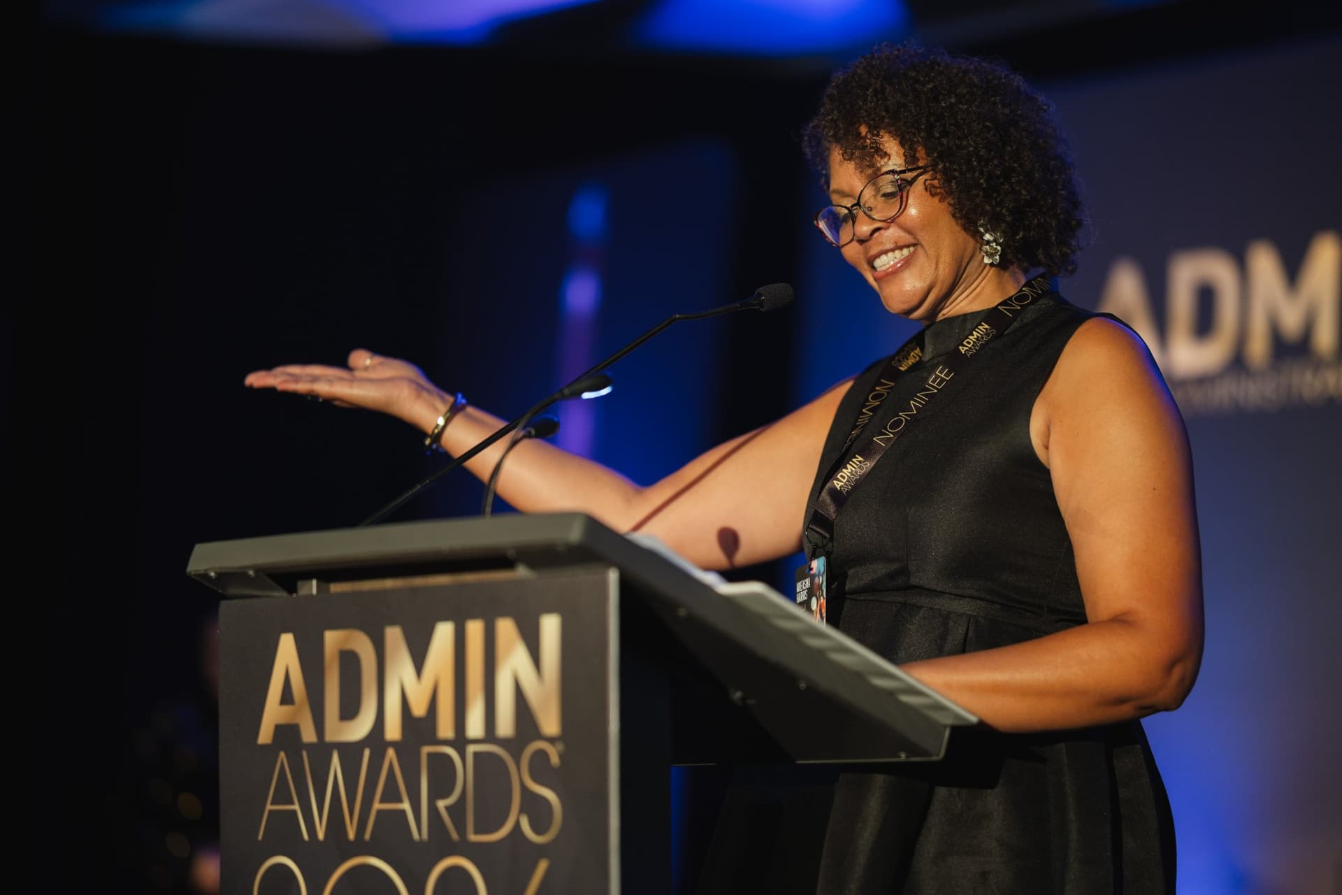 Joyful honoree gesturing to the crowd during her acceptance speech at Admin Awards 2026 at SFO Marriott Waterfront, Burlingame by JY Studio