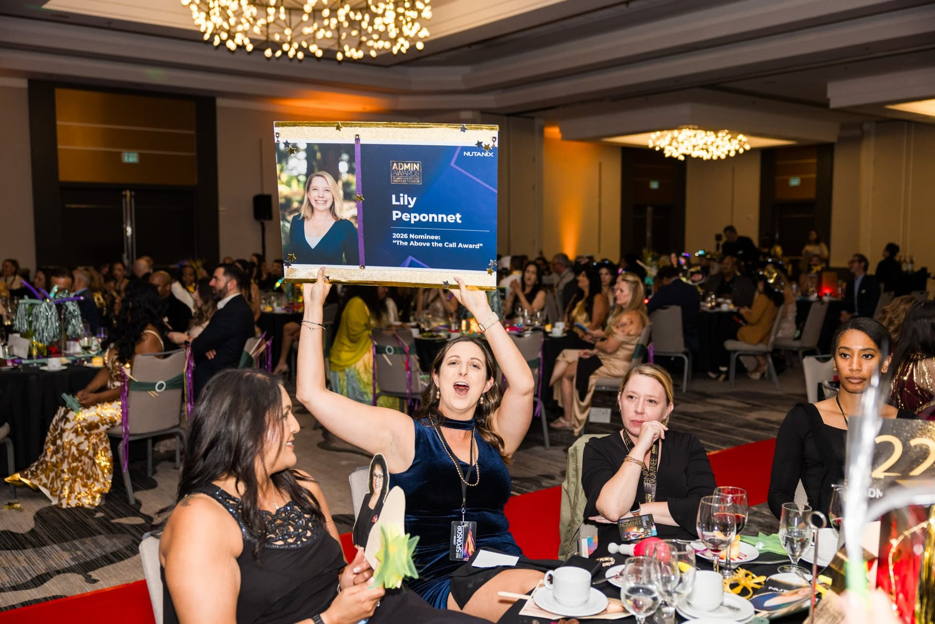 Table of guests cheering and holding up a nominee photo sign at Admin Awards 2026 at SFO Marriott Waterfront, Burlingame by JY Studio