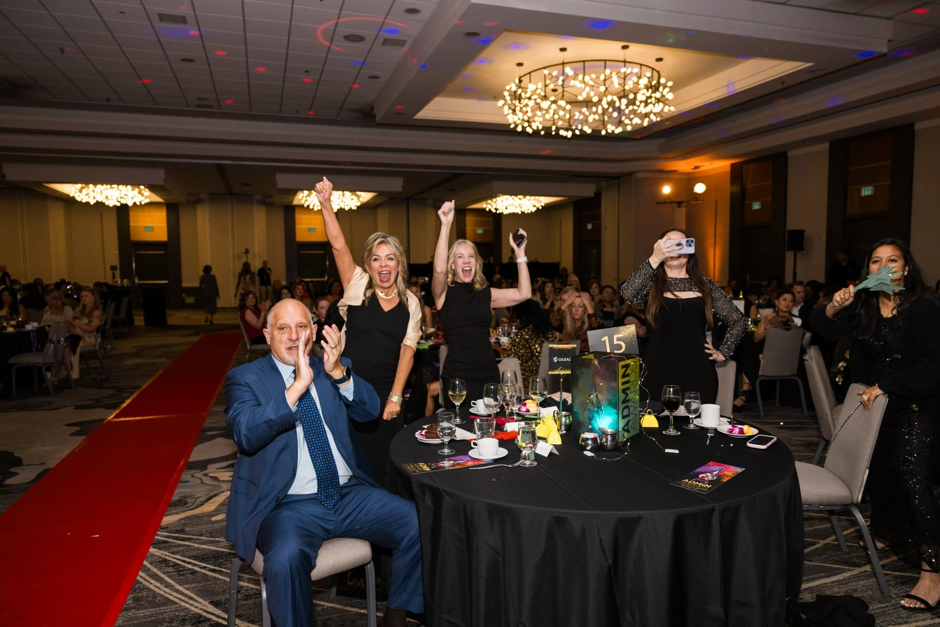 Guests jumping up and cheering at their table as a winner is announced at Admin Awards 2026 at SFO Marriott Waterfront, Burlingame by JY Studio