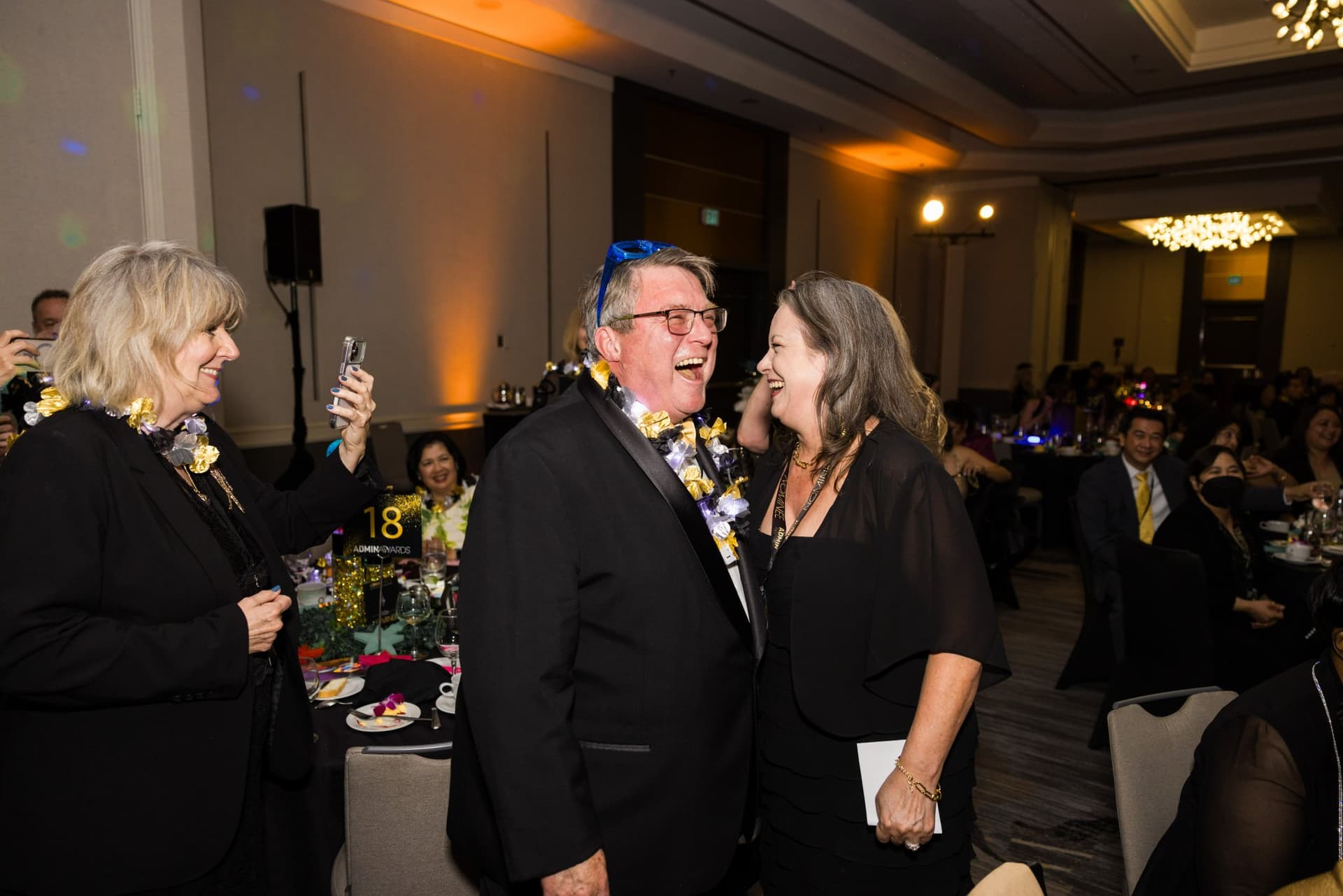 Guests laughing and celebrating in the ballroom wearing leis at Admin Awards 2026 at SFO Marriott Waterfront, Burlingame by JY Studio