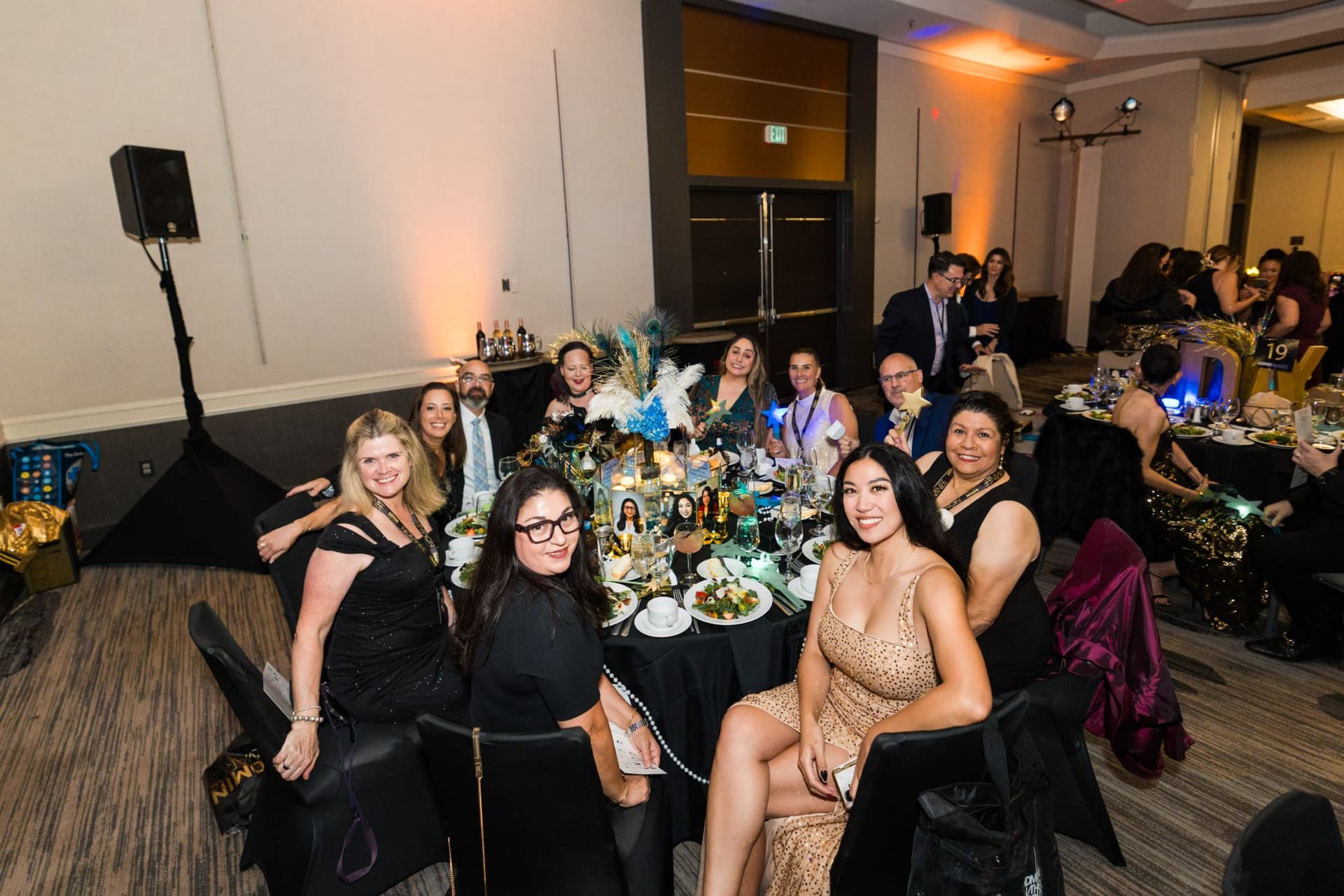 Table of guests posing around a festive centerpiece in the ballroom at Admin Awards 2026 at SFO Marriott Waterfront, Burlingame by JY Studio