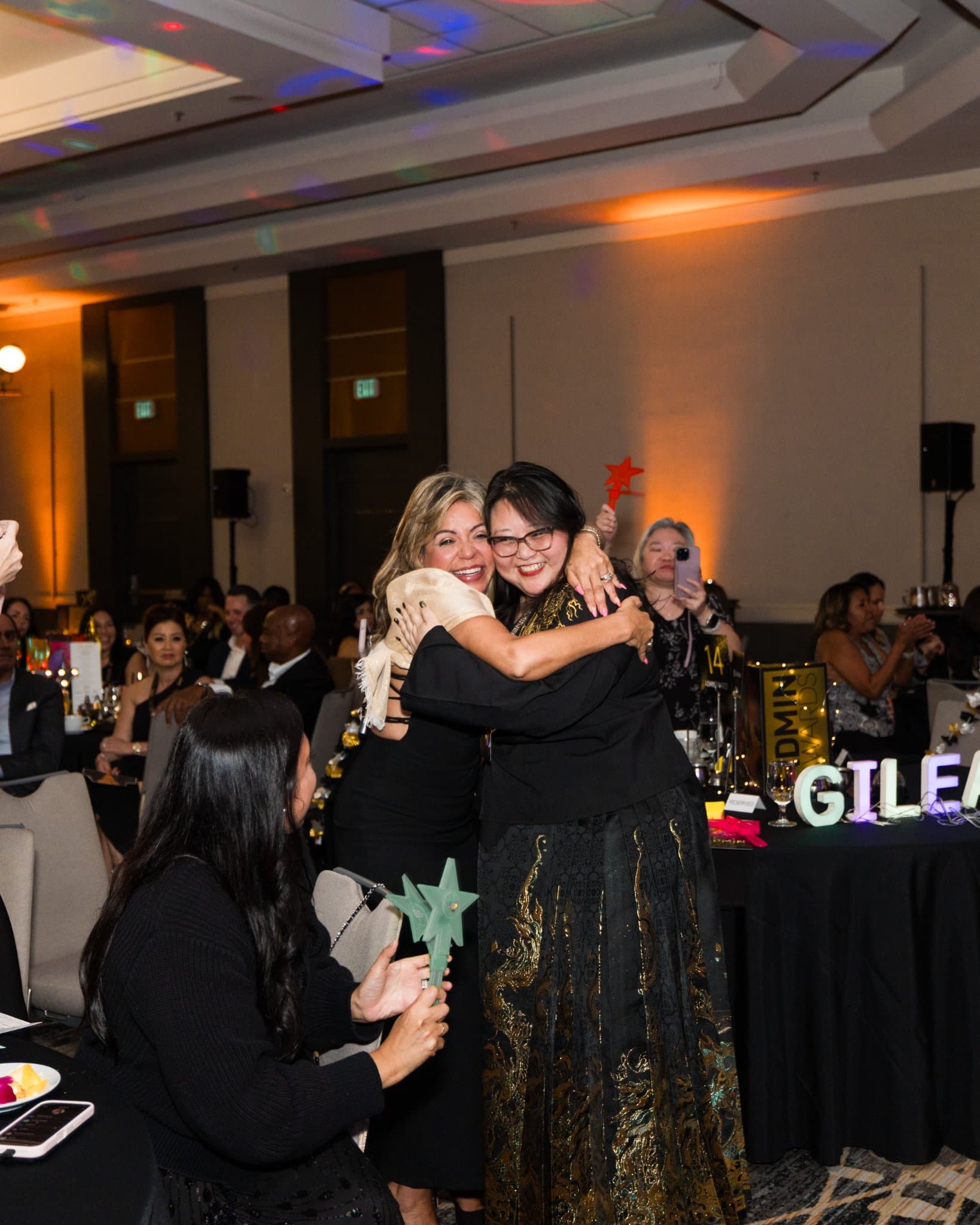 Guests embracing in celebration at their table after a winner is announced at Admin Awards 2026 at SFO Marriott Waterfront, Burlingame by JY Studio