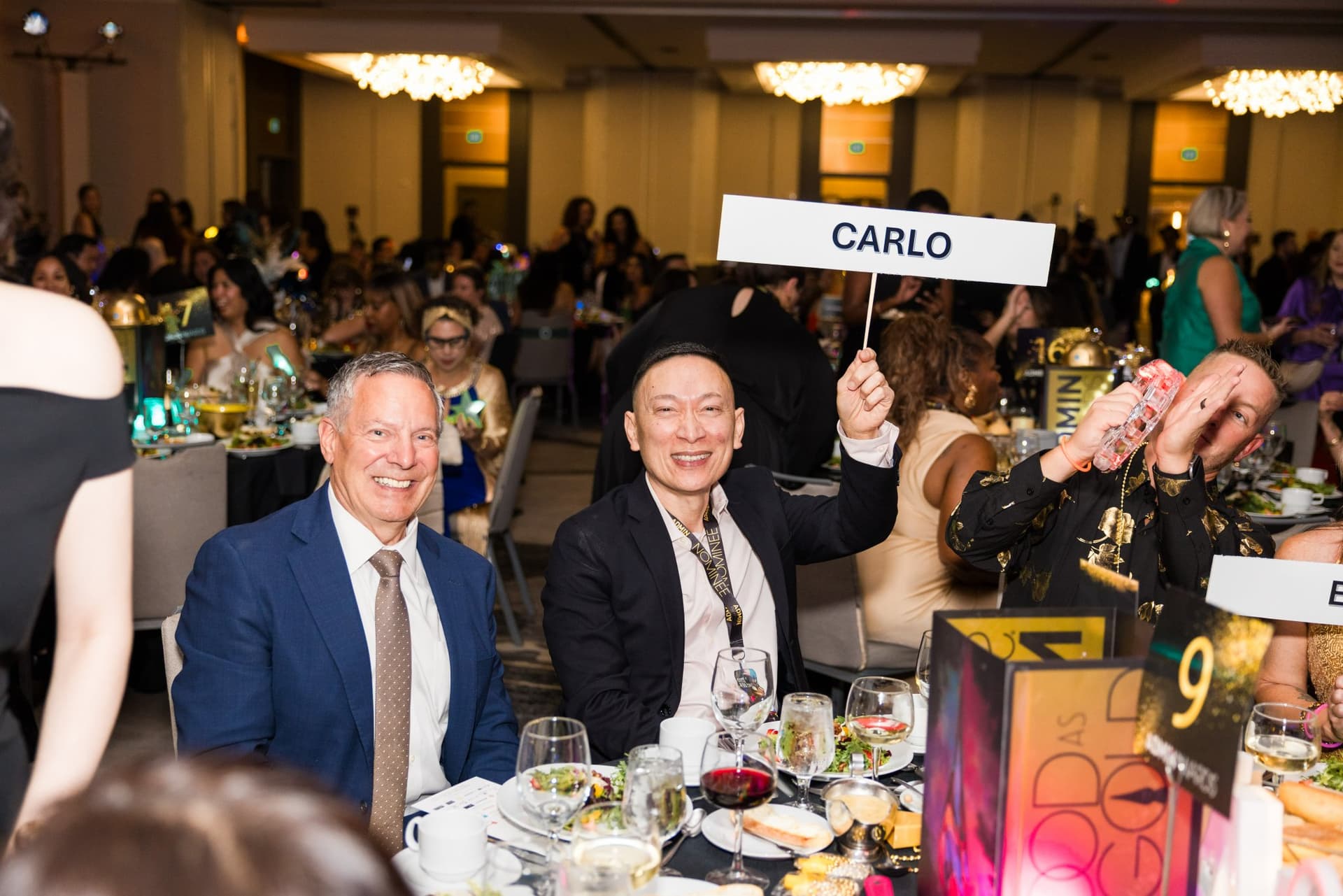Guests at their banquet table holding a name sign during the ceremony at Admin Awards 2026 at SFO Marriott Waterfront, Burlingame by JY Studio