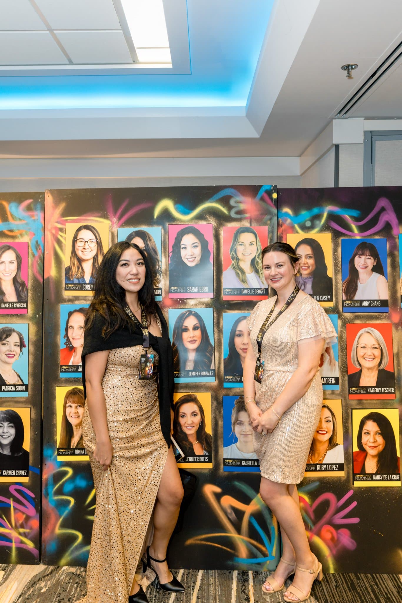 Two guests posing in front of the colorful nominee portrait wall at Admin Awards 2026 at SFO Marriott Waterfront, Burlingame by JY Studio