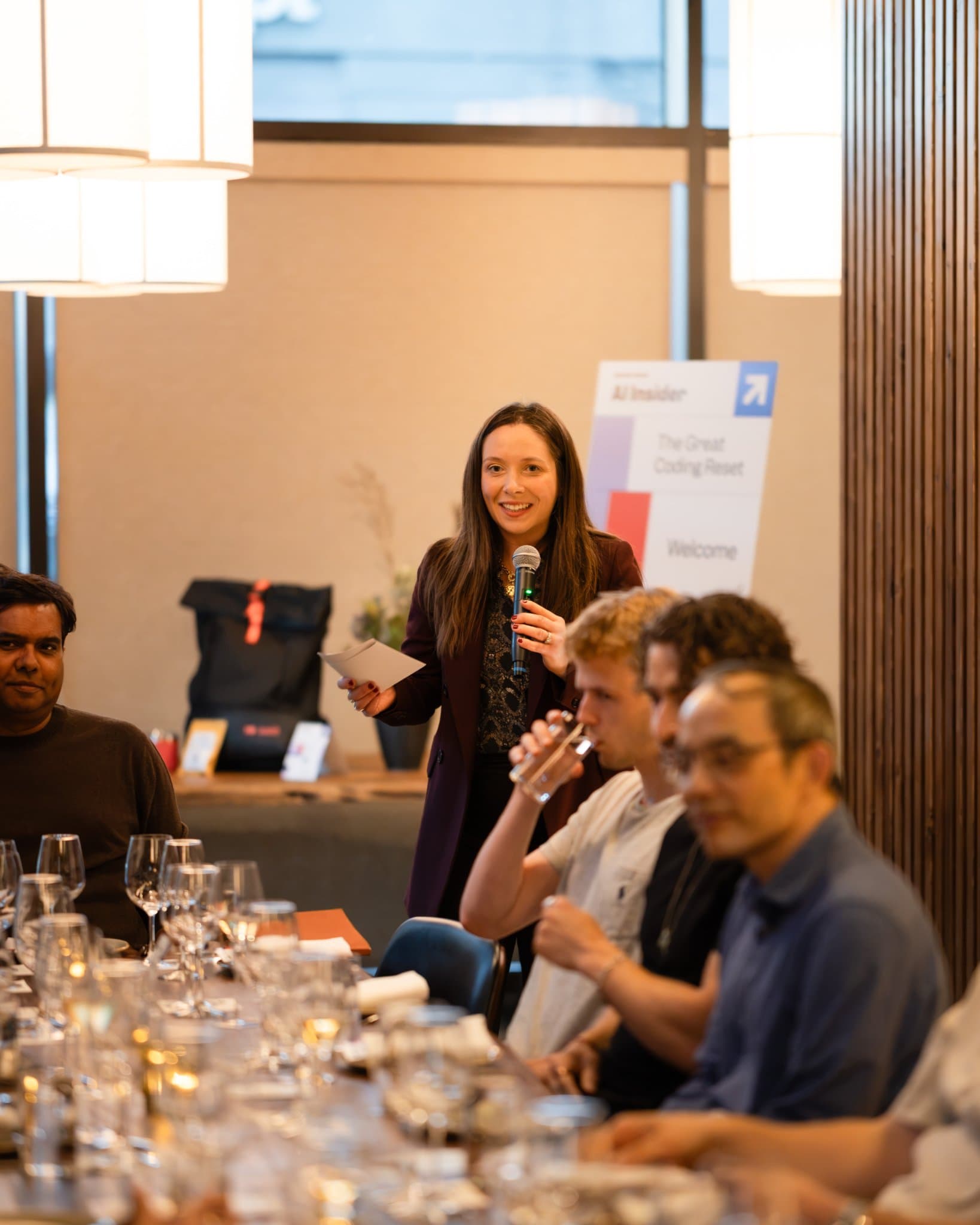 Business Insider host welcoming guests with a microphone beside the AI Insider sign at the Business Insider AI Insider executive dinner The Great Coding Reset during SF Tech Week 2026 in San Francisco by JY Studio
