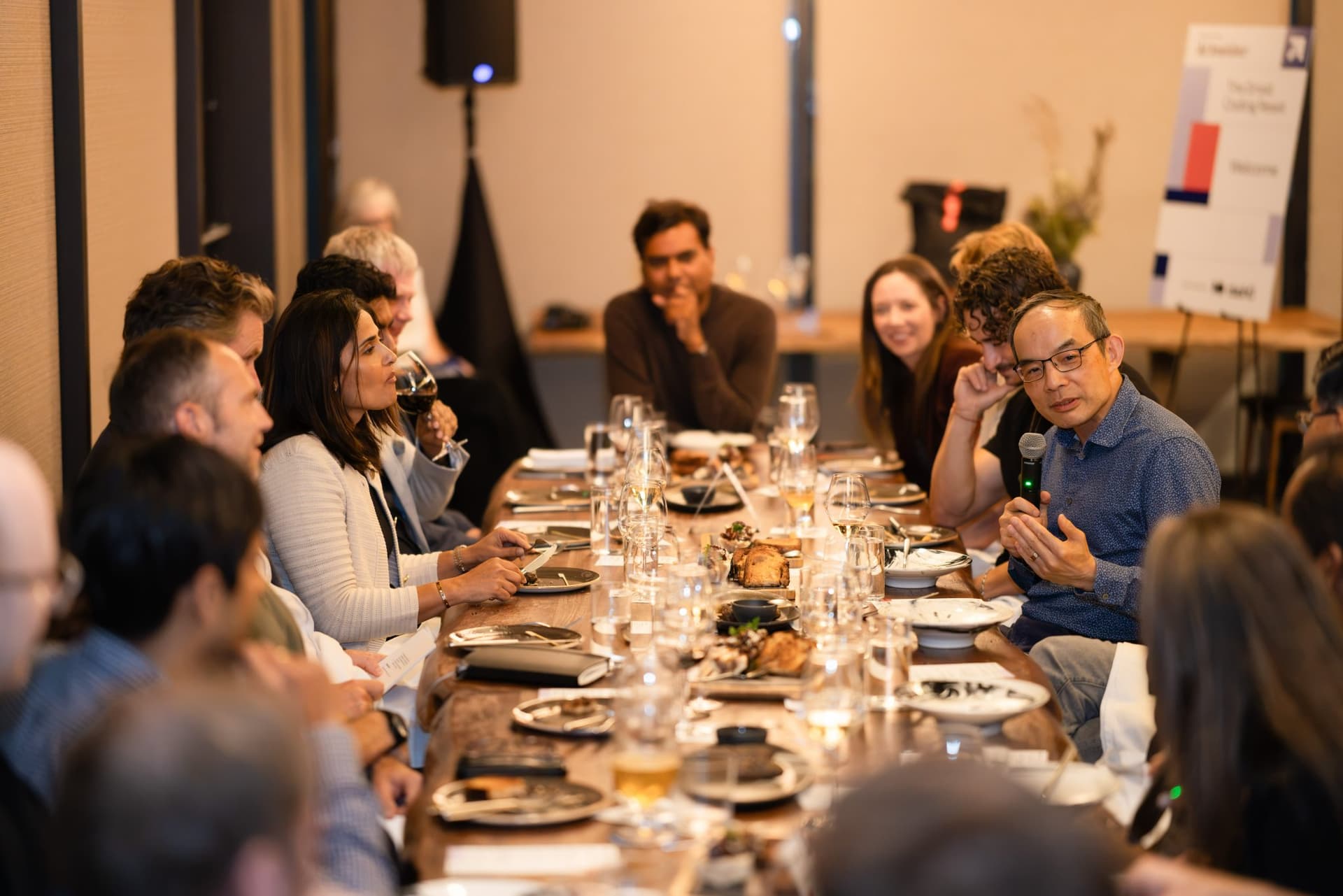 Wide view of the dinner table as an executive speaks at the Business Insider AI Insider executive dinner The Great Coding Reset during SF Tech Week 2026 in San Francisco by JY Studio