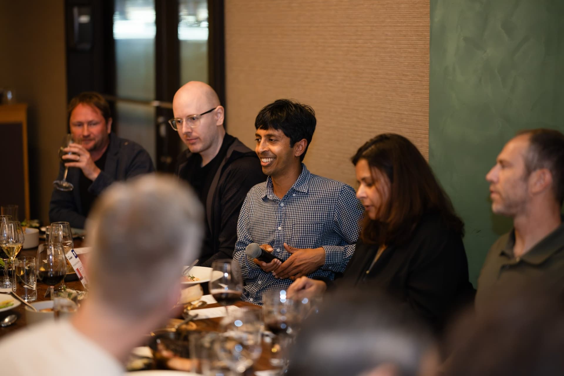 Executive in a checkered shirt laughing with the table at the Business Insider AI Insider executive dinner The Great Coding Reset during SF Tech Week 2026 in San Francisco by JY Studio