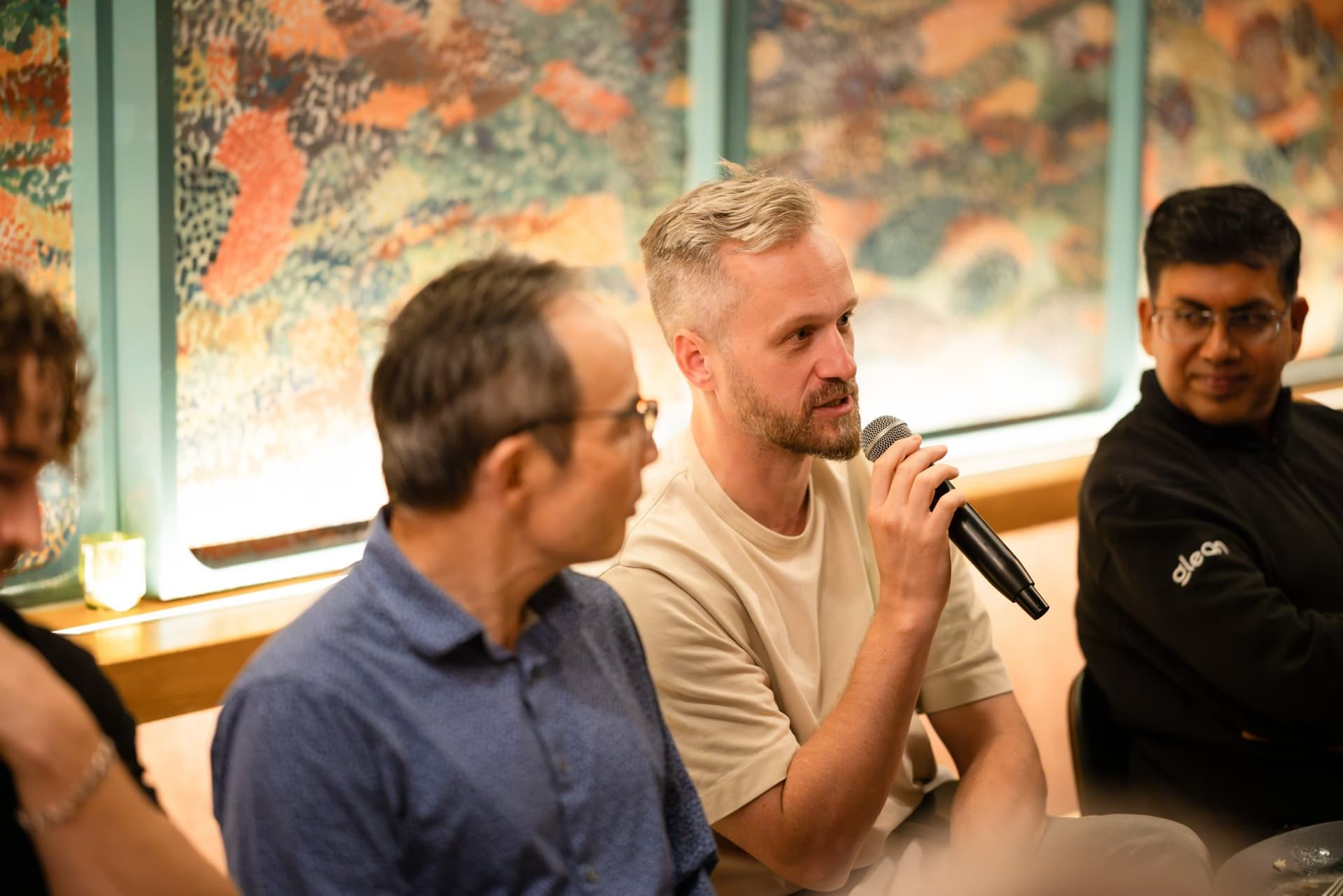 Executive speaking with a microphone beside the illuminated wall panels at the Business Insider AI Insider executive dinner The Great Coding Reset during SF Tech Week 2026 in San Francisco by JY Studio