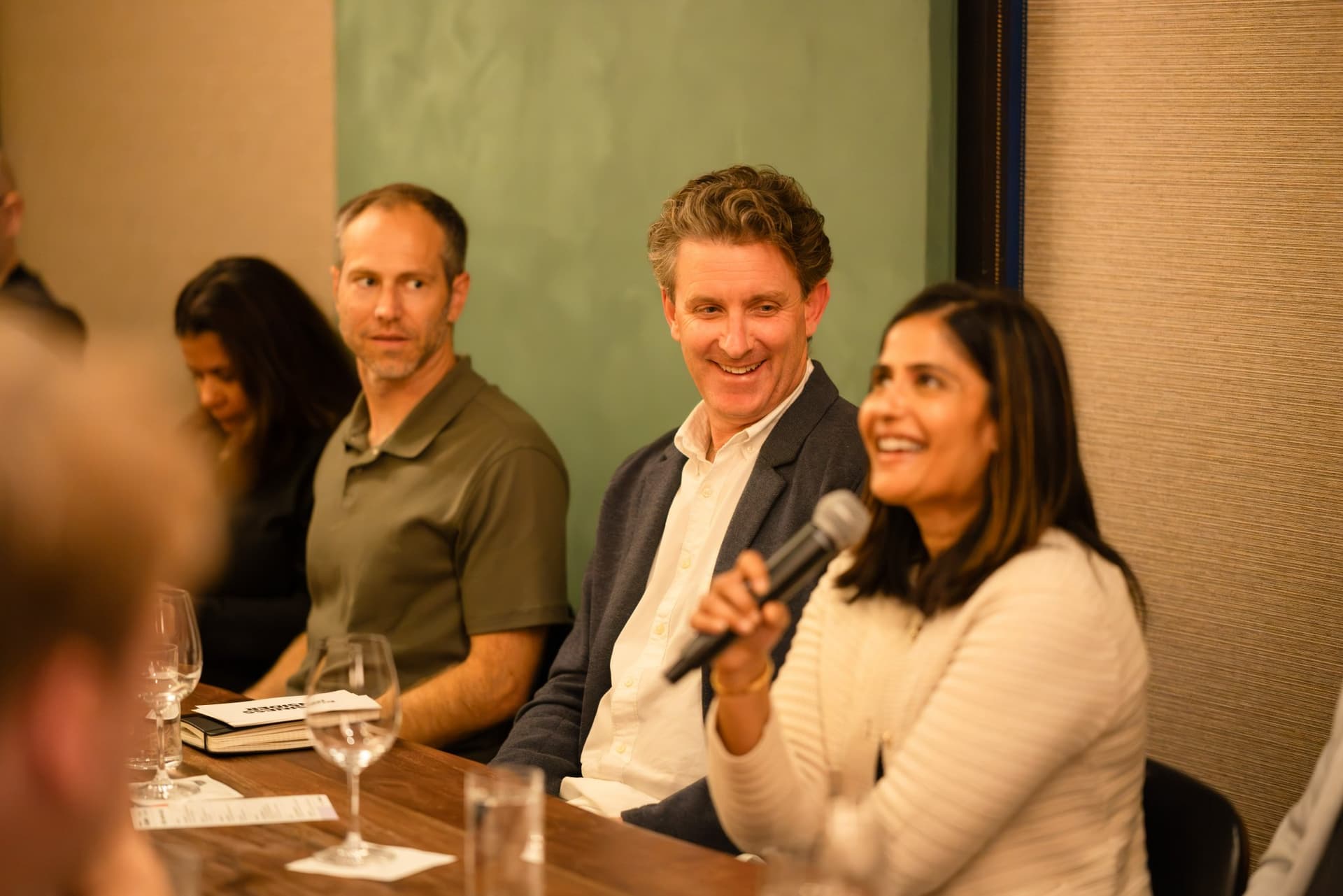 Woman executive laughing while speaking into the microphone at the Business Insider AI Insider executive dinner The Great Coding Reset during SF Tech Week 2026 in San Francisco by JY Studio