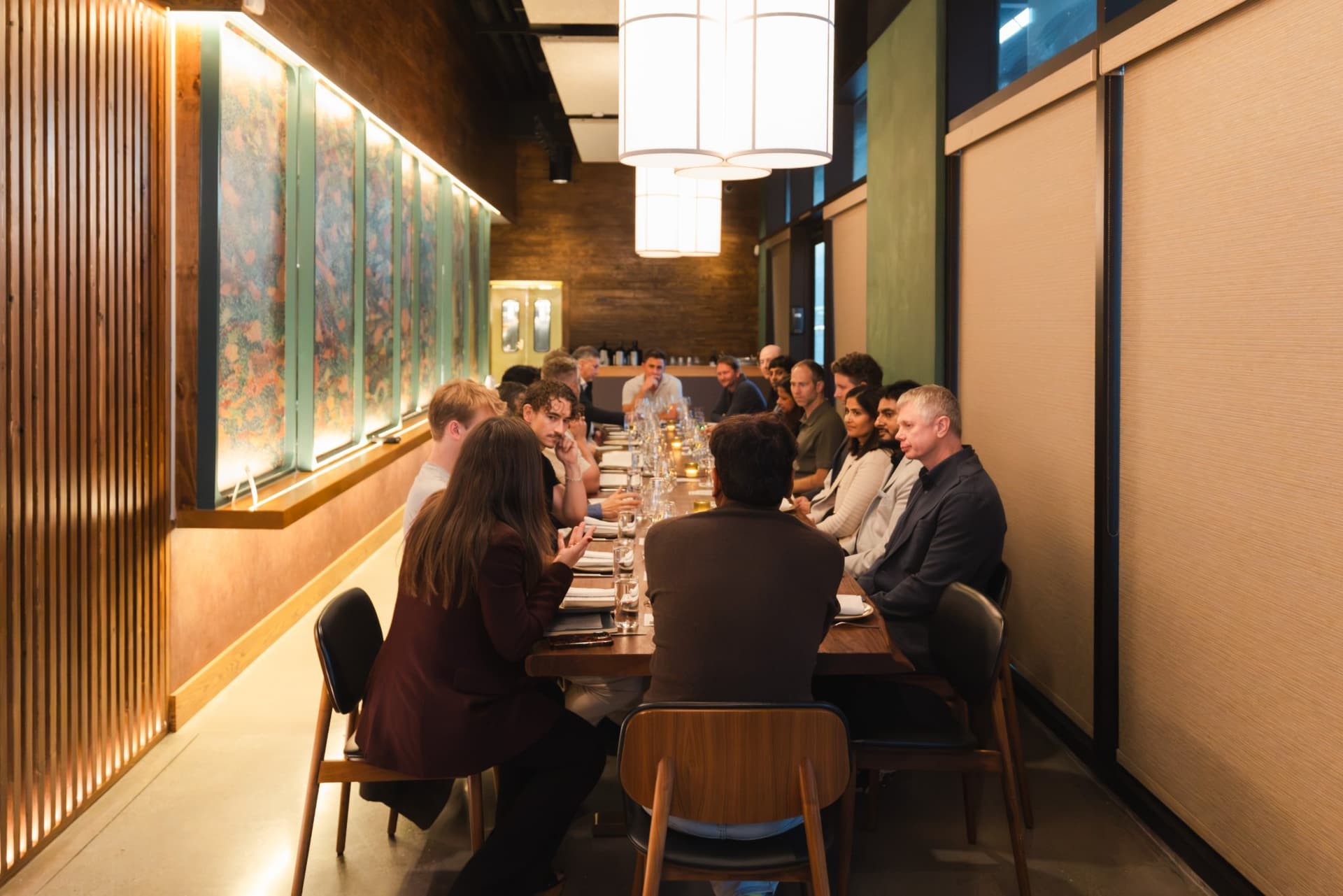 Long dinner table full of tech executives mid-conversation at the Business Insider AI Insider executive dinner The Great Coding Reset during SF Tech Week 2026 in San Francisco by JY Studio