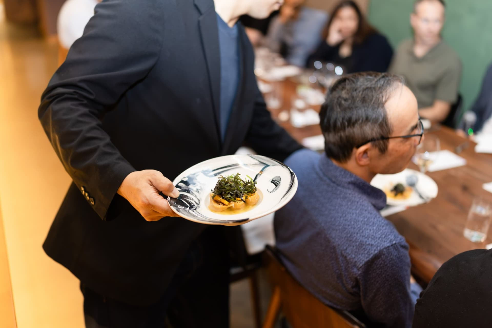 Server presenting a plated dish to a guest at the Business Insider AI Insider executive dinner The Great Coding Reset during SF Tech Week 2026 in San Francisco by JY Studio