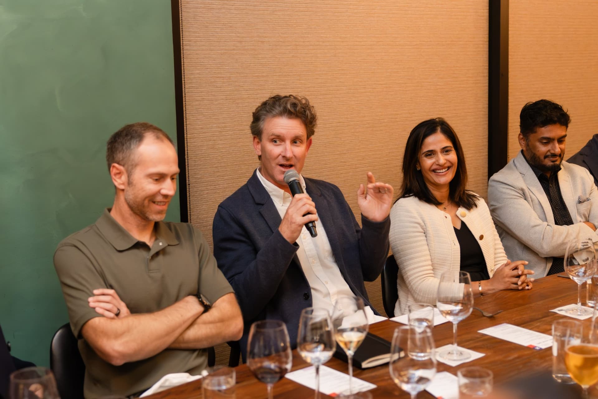 Executive speaking with a microphone as tablemates react at the Business Insider AI Insider executive dinner The Great Coding Reset during SF Tech Week 2026 in San Francisco by JY Studio