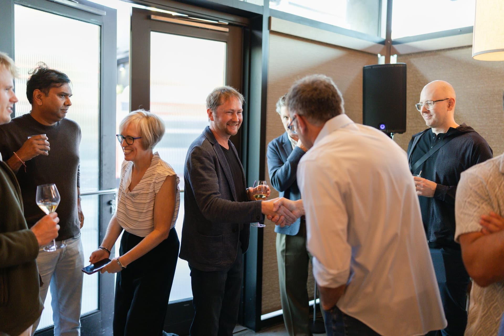 Executives shaking hands by the windows during the reception at the Business Insider AI Insider executive dinner The Great Coding Reset during SF Tech Week 2026 in San Francisco by JY Studio