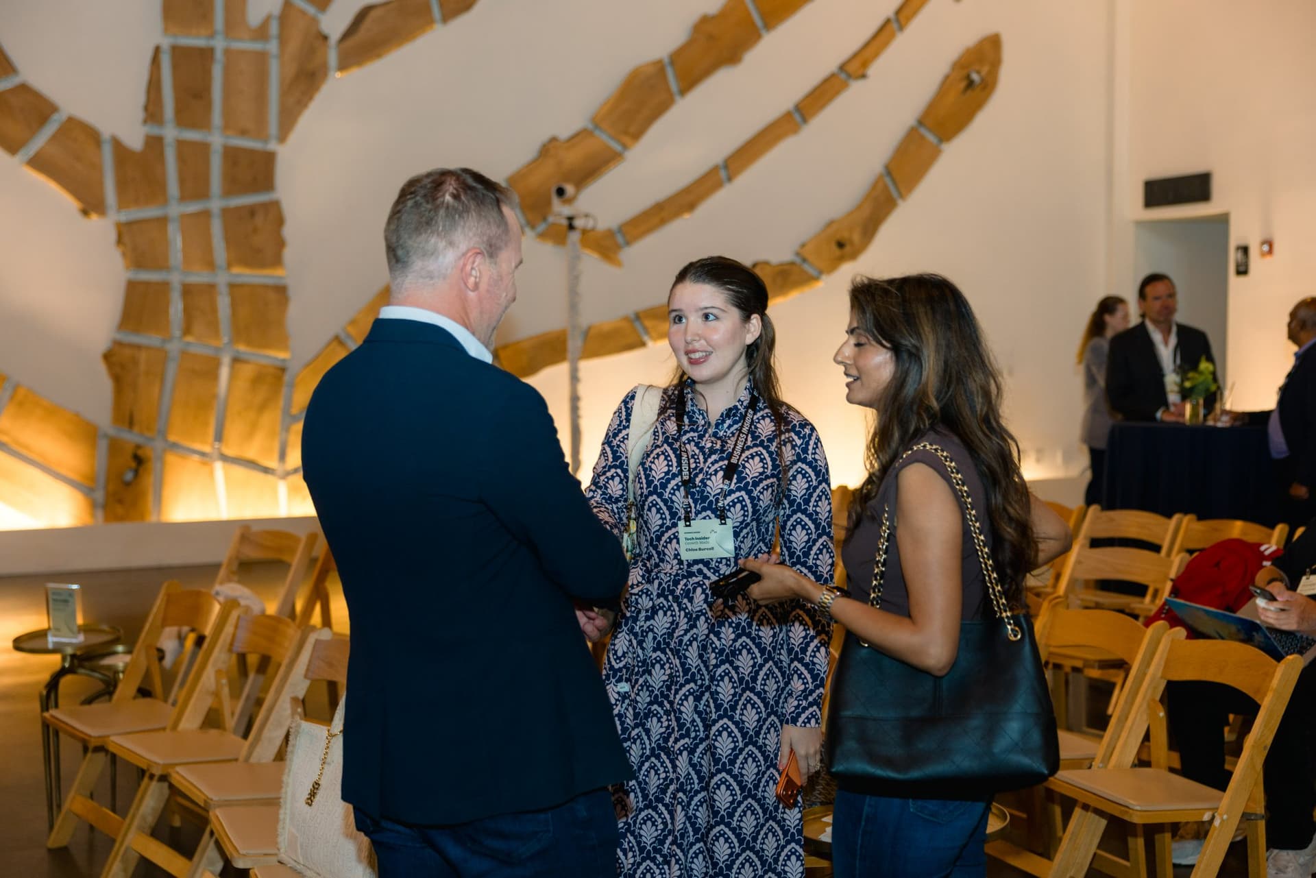 Three attendees talking among the event chairs at Business Insider Tech Insider: Growth Mode at The Pearl SF during SF Tech Week 2026 in San Francisco by JY Studio