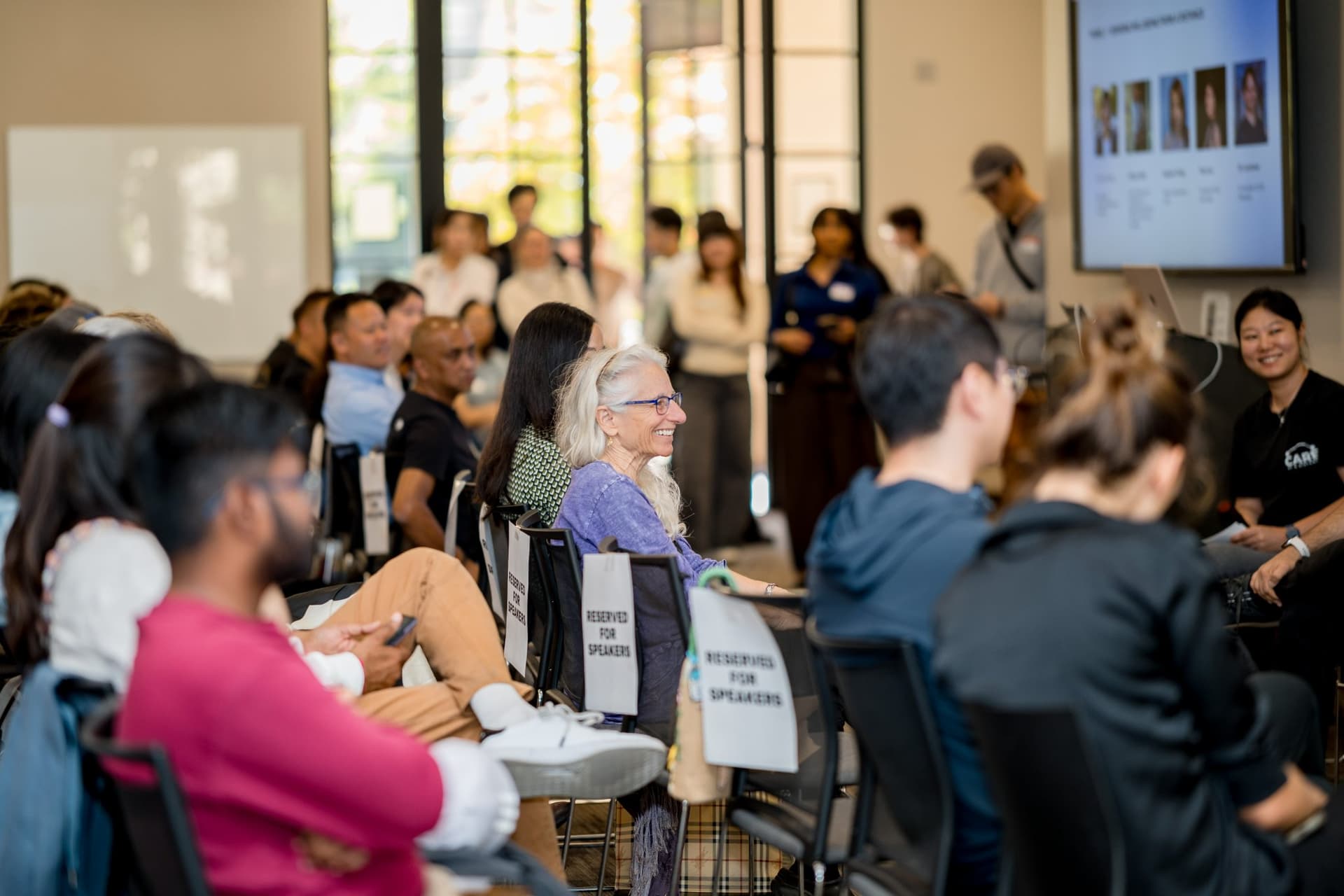Attendees filling the seats around the Reserved for Speakers chairs as Panel 1 begins at Care at a Distance: AI, Sensors, Robotics and the Future of Aging, SF Tech Week 2026 at EVGR, Stanford University by JY Studio