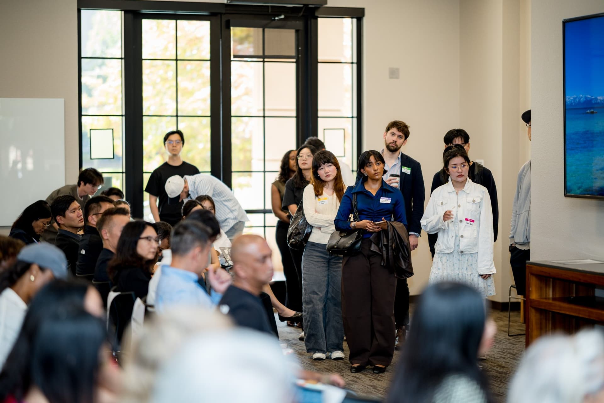 Standing-room crowd lining the back of the room during the panel at Care at a Distance: AI, Sensors, Robotics and the Future of Aging, SF Tech Week 2026 at EVGR, Stanford University by JY Studio