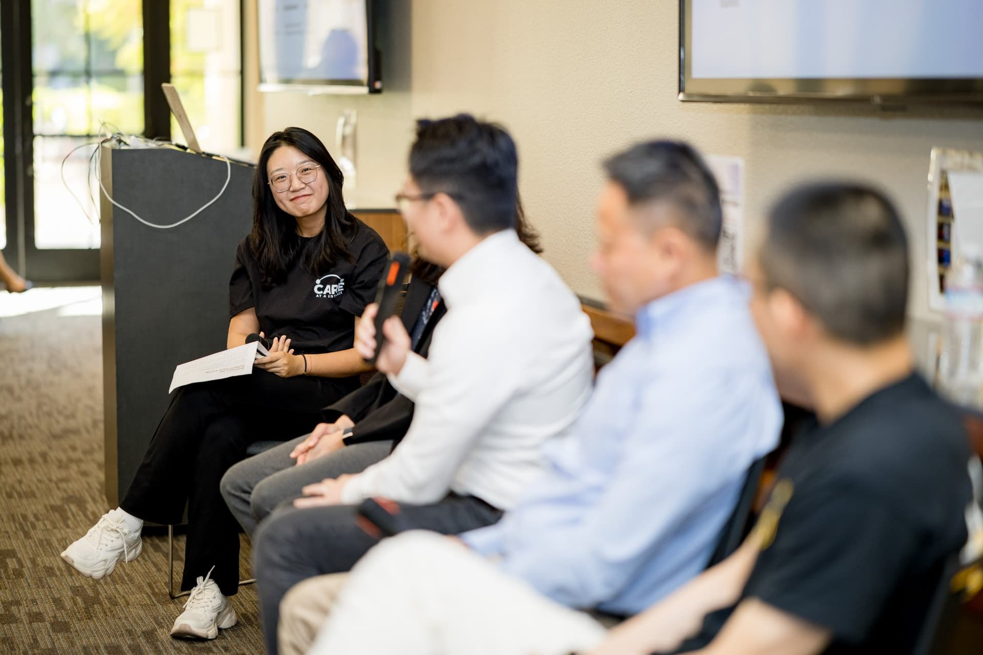 Smiling moderator listening to a panelist answer during Panel 2 "Robotics for Independent Living" at Care at a Distance: AI, Sensors, Robotics and the Future of Aging, SF Tech Week 2026 at EVGR, Stanford University by JY Studio