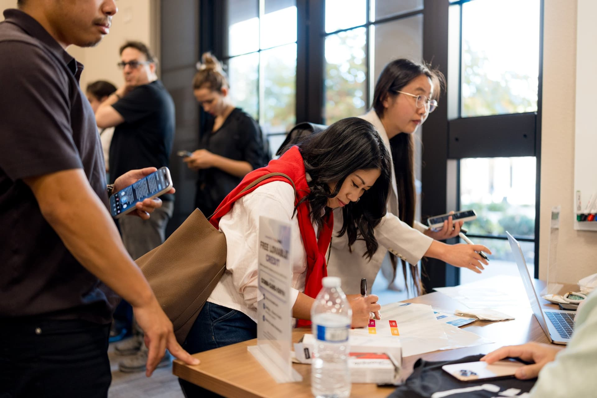 Guests filling out name tags at the busy check-in table at Care at a Distance: AI, Sensors, Robotics and the Future of Aging, SF Tech Week 2026 at EVGR, Stanford University by JY Studio