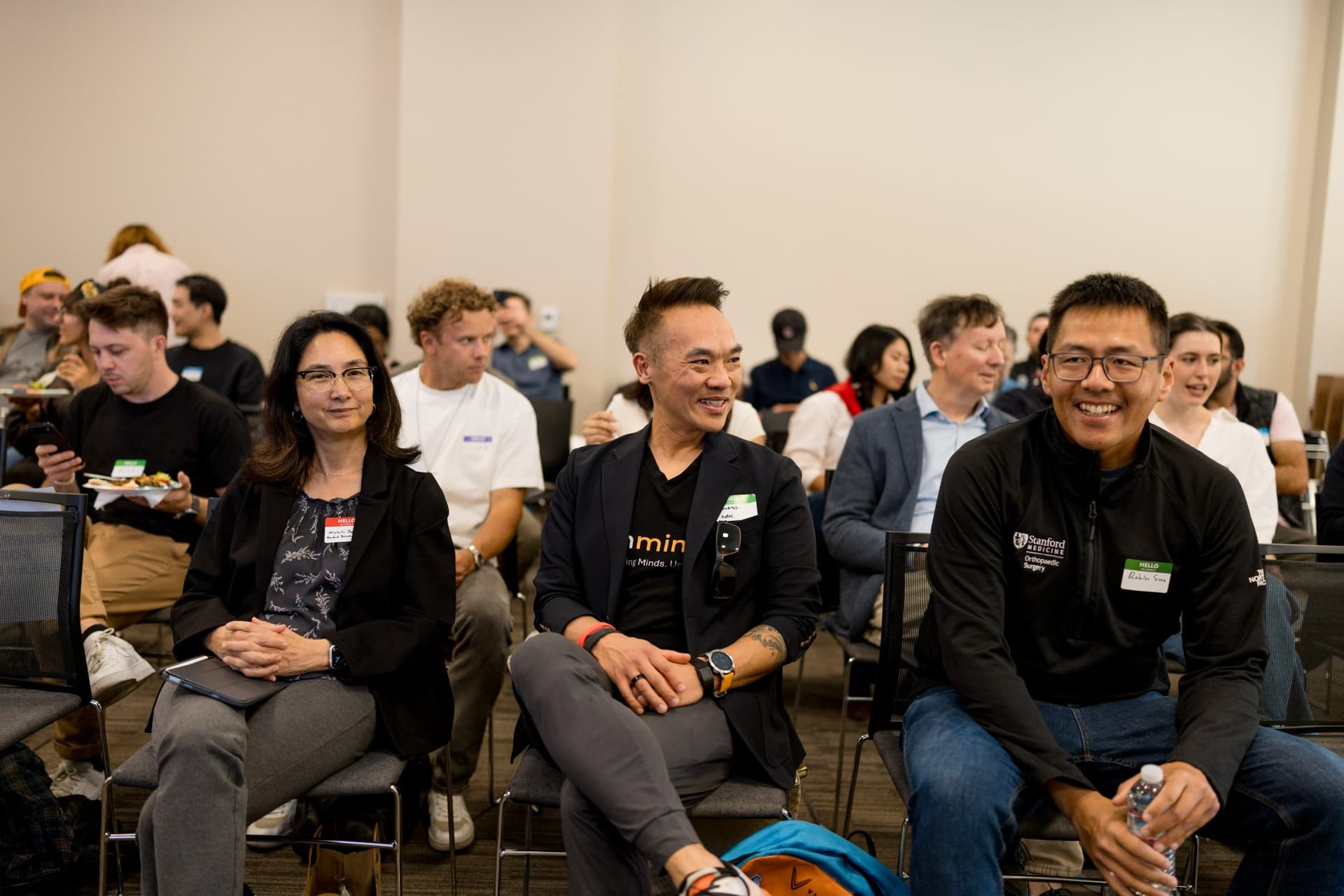 Attendees smiling in their seats waiting for the panels to begin at Care at a Distance: AI, Sensors, Robotics and the Future of Aging, SF Tech Week 2026 at EVGR, Stanford University by JY Studio