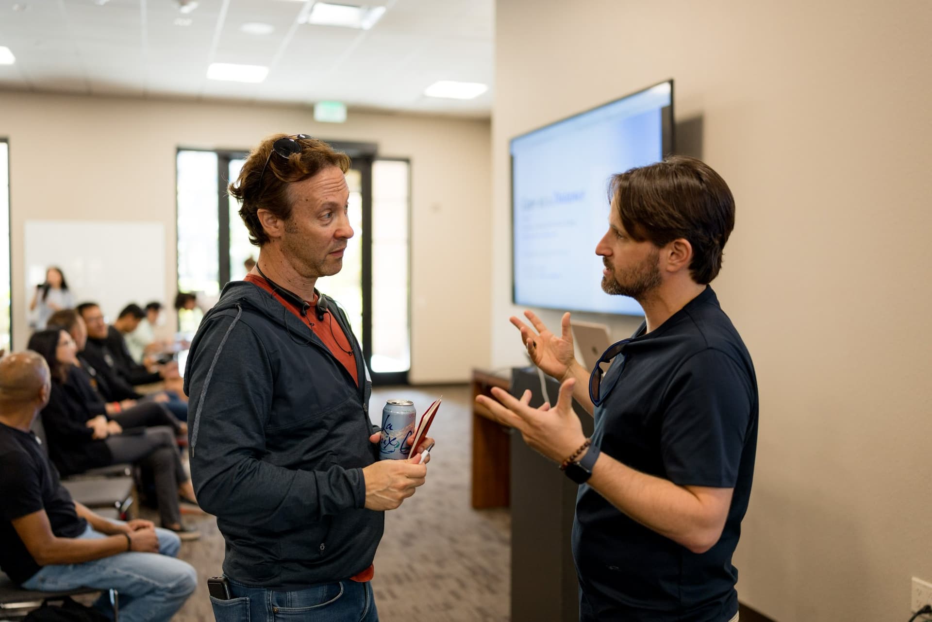 Two guests in conversation before the program at Care at a Distance: AI, Sensors, Robotics and the Future of Aging, SF Tech Week 2026 at EVGR, Stanford University by JY Studio