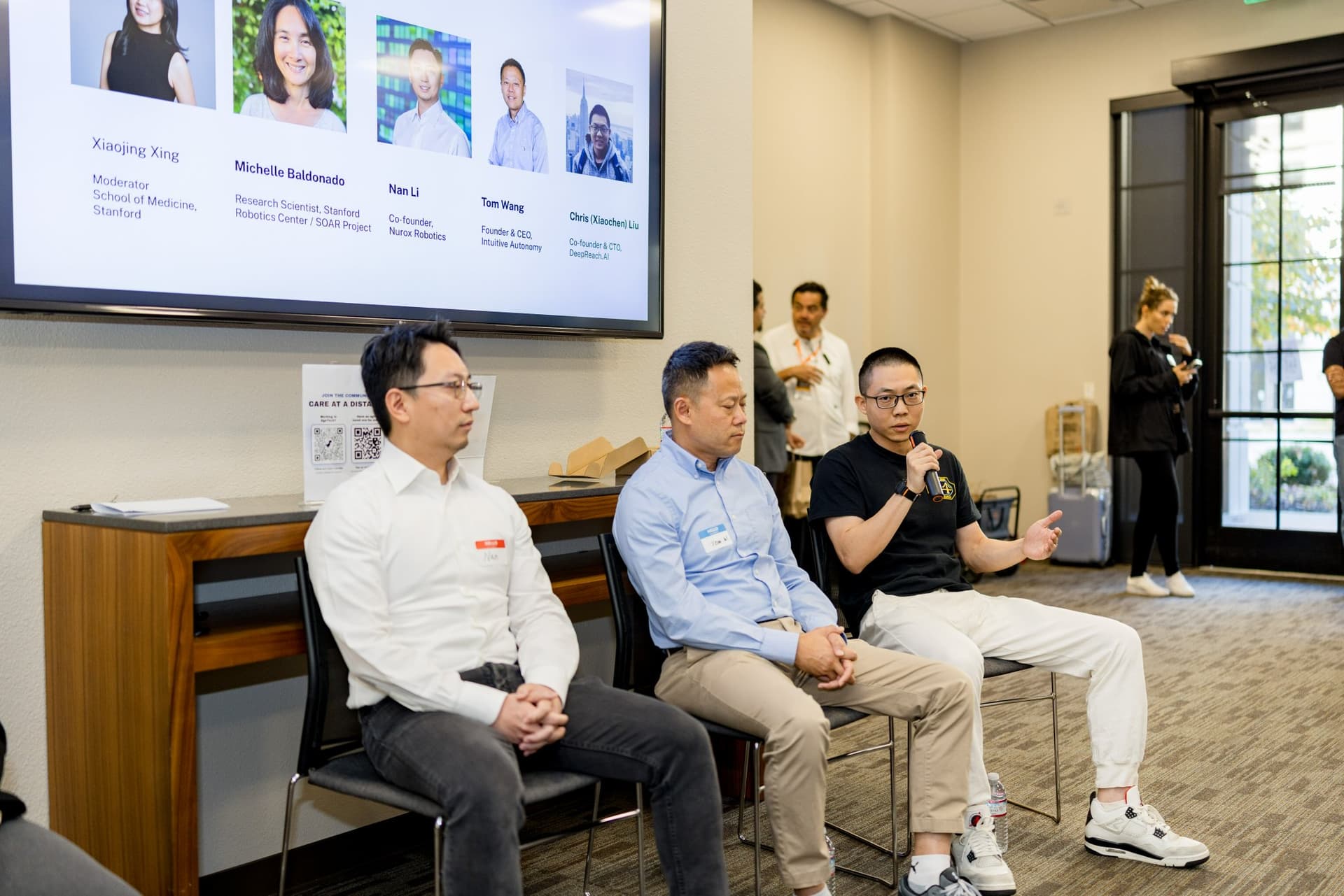 Panelist speaking during Panel 2 "Robotics for Independent Living" while the moderator listens at Care at a Distance: AI, Sensors, Robotics and the Future of Aging, SF Tech Week 2026 at EVGR, Stanford University by JY Studio