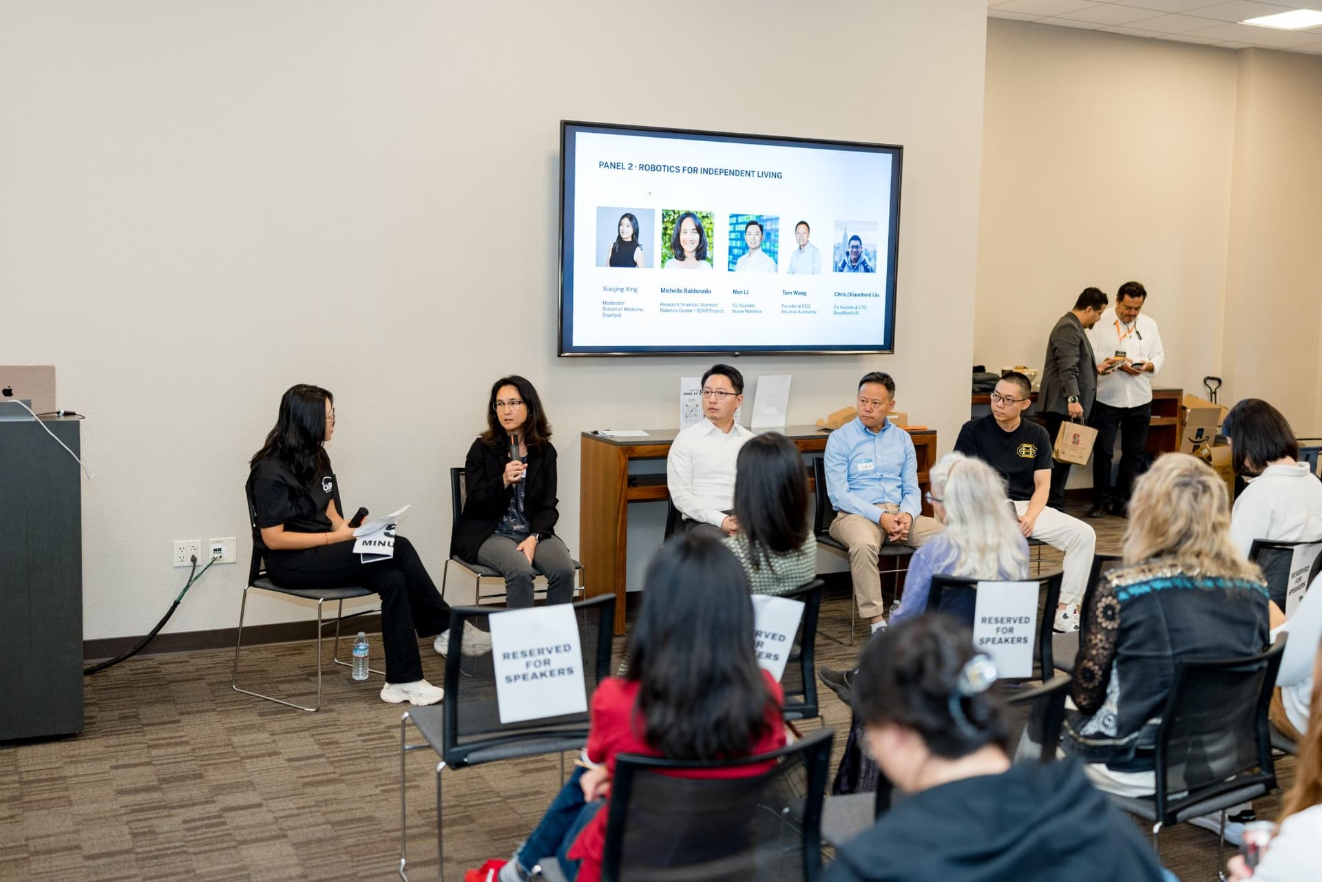 Wide shot of the moderator and panelists of Panel 2 "Robotics for Independent Living" at Care at a Distance: AI, Sensors, Robotics and the Future of Aging, SF Tech Week 2026 at EVGR, Stanford University by JY Studio