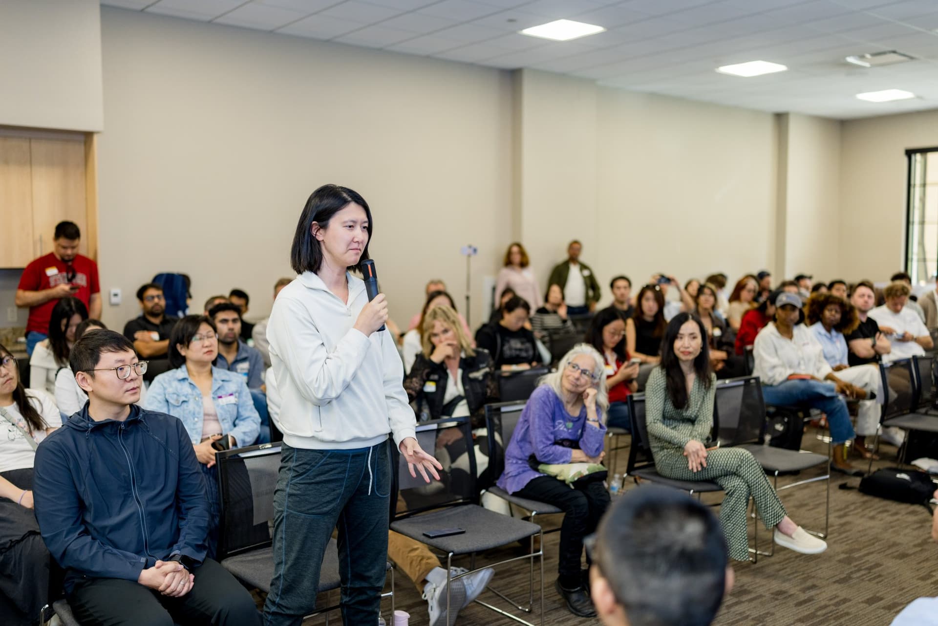 Attendee standing to ask the robotics panel a question at Care at a Distance: AI, Sensors, Robotics and the Future of Aging, SF Tech Week 2026 at EVGR, Stanford University by JY Studio