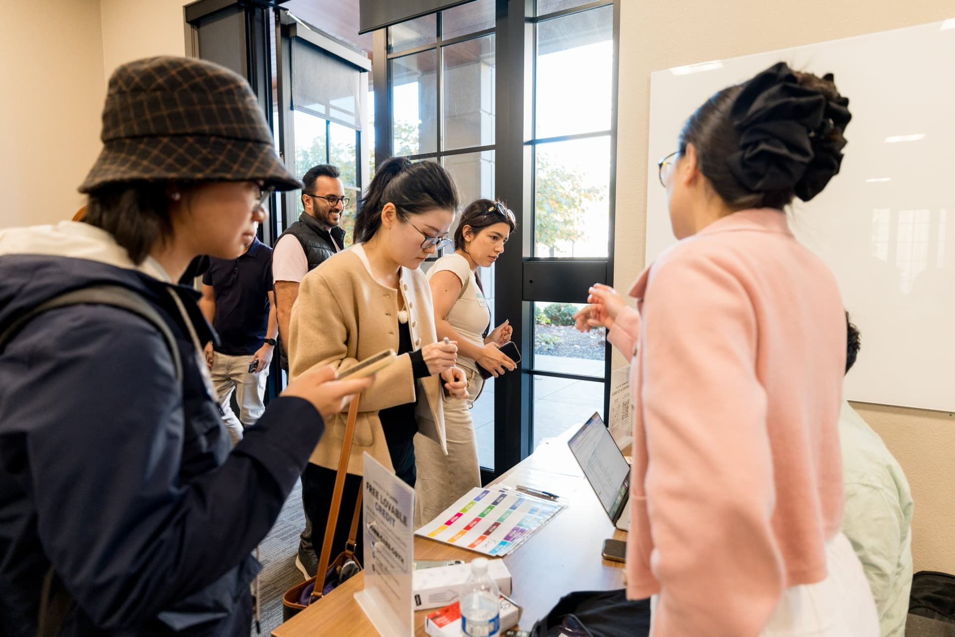 Attendees chatting with the host team at the check-in table at Care at a Distance: AI, Sensors, Robotics and the Future of Aging, SF Tech Week 2026 at EVGR, Stanford University by JY Studio