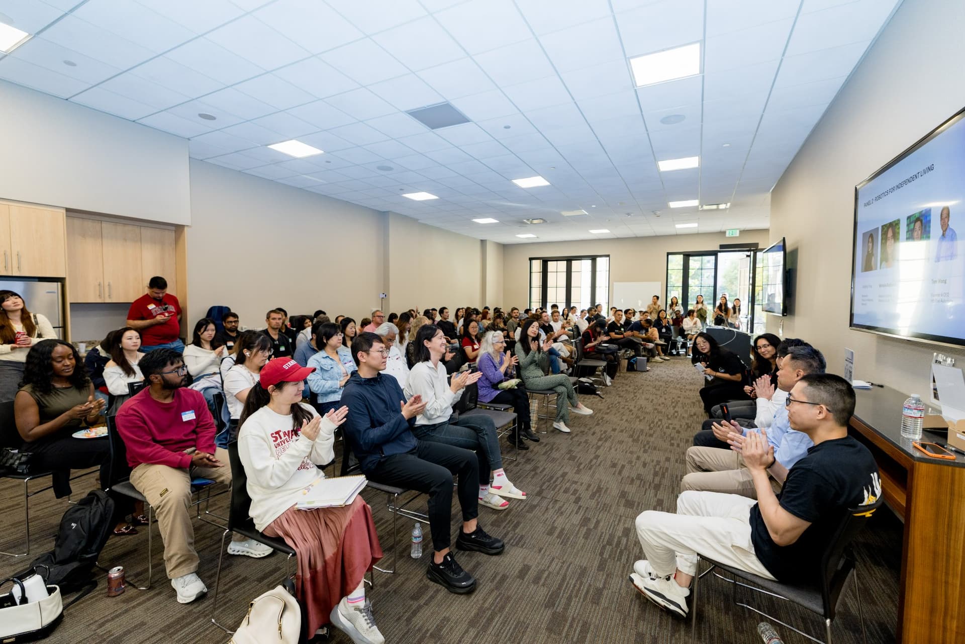 Attendees applauding the panelists at Care at a Distance: AI, Sensors, Robotics and the Future of Aging, SF Tech Week 2026 at EVGR, Stanford University by JY Studio
